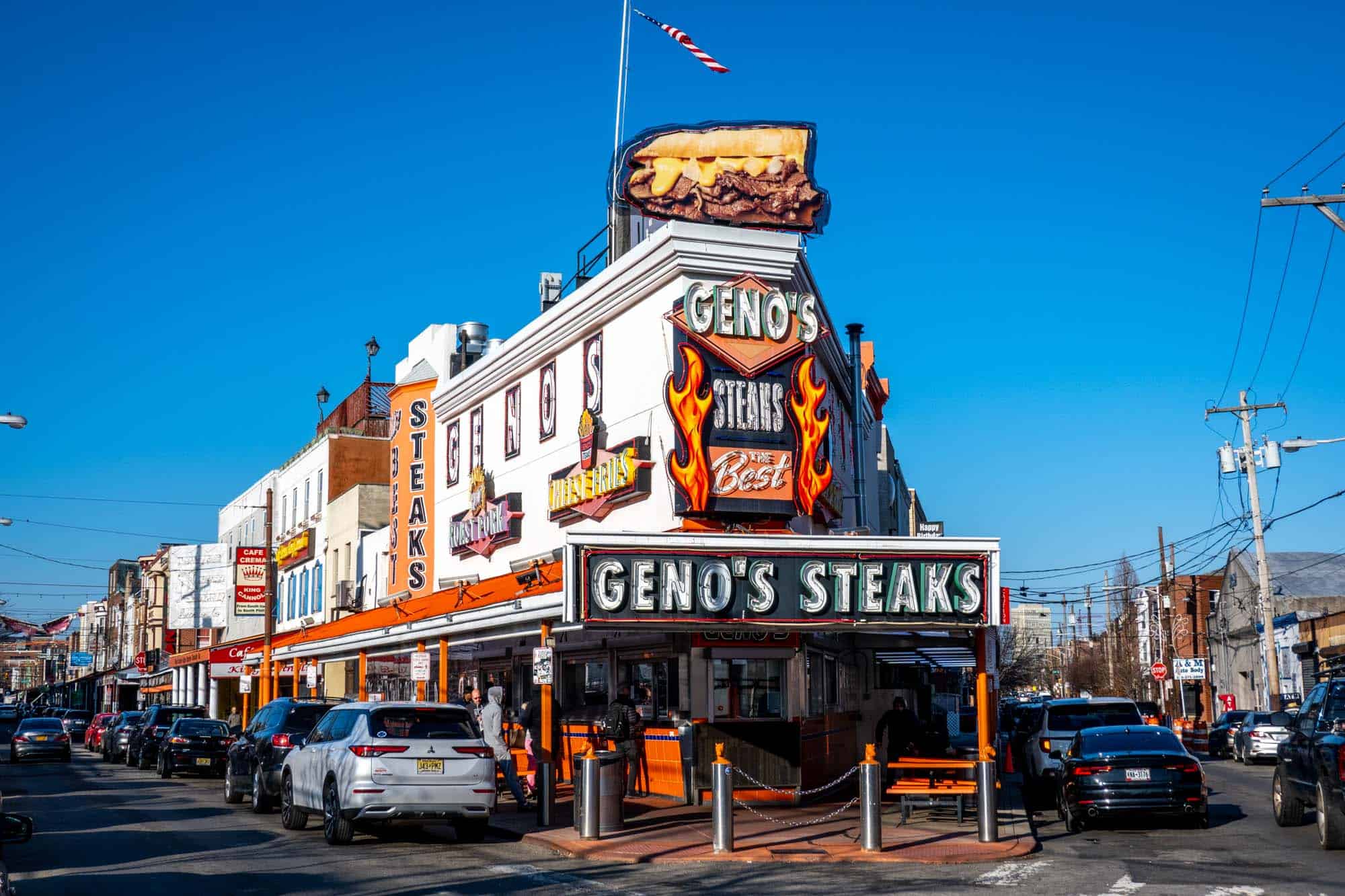 Exterior of a corner restaurant with a sign: "Geno's Steaks." 