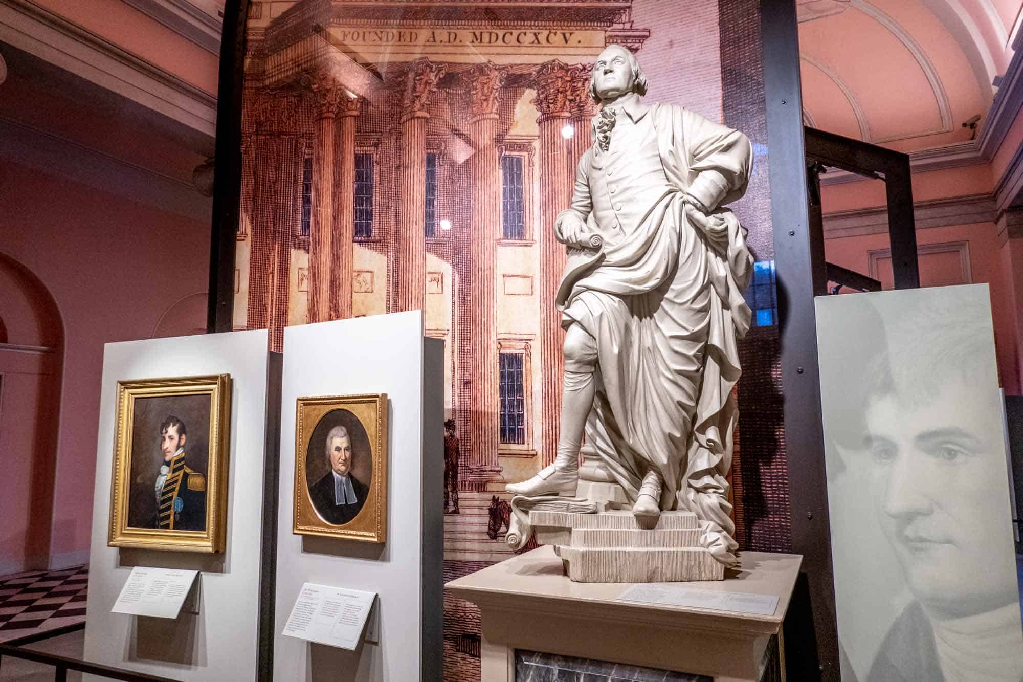 Portraits of historical figures on display beside a marble statue of Geroge Washington