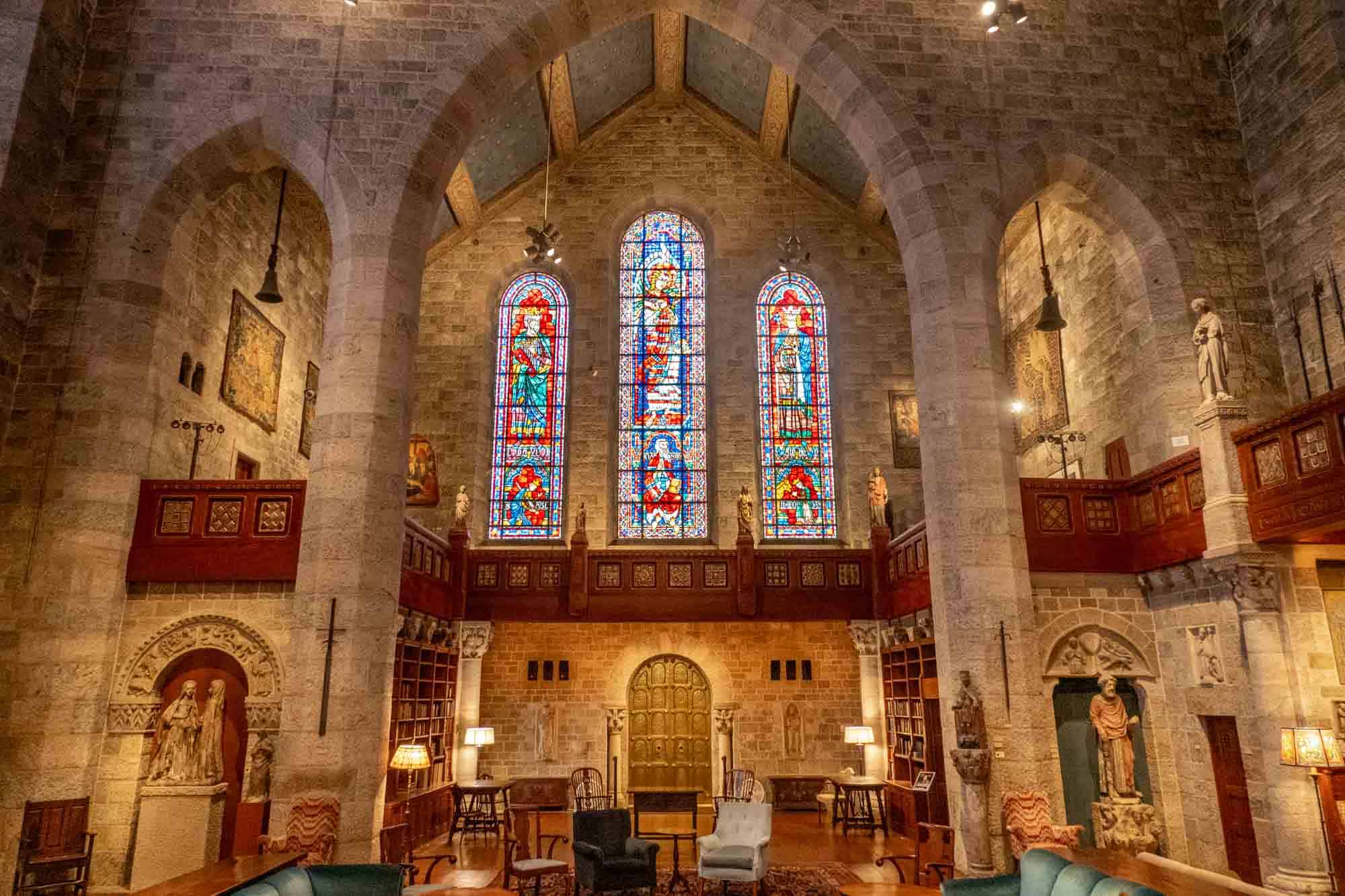 Stone room with vaulted ceiling and arches, stained glass windows, and sculptures