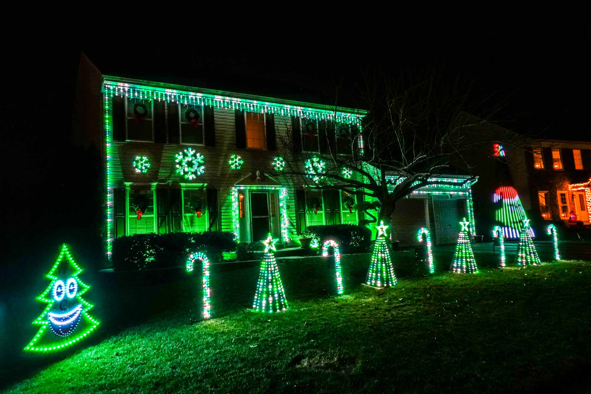 House decorated with snowflake-shaped Christmas lights and lit up candy canes and trees in the yard.