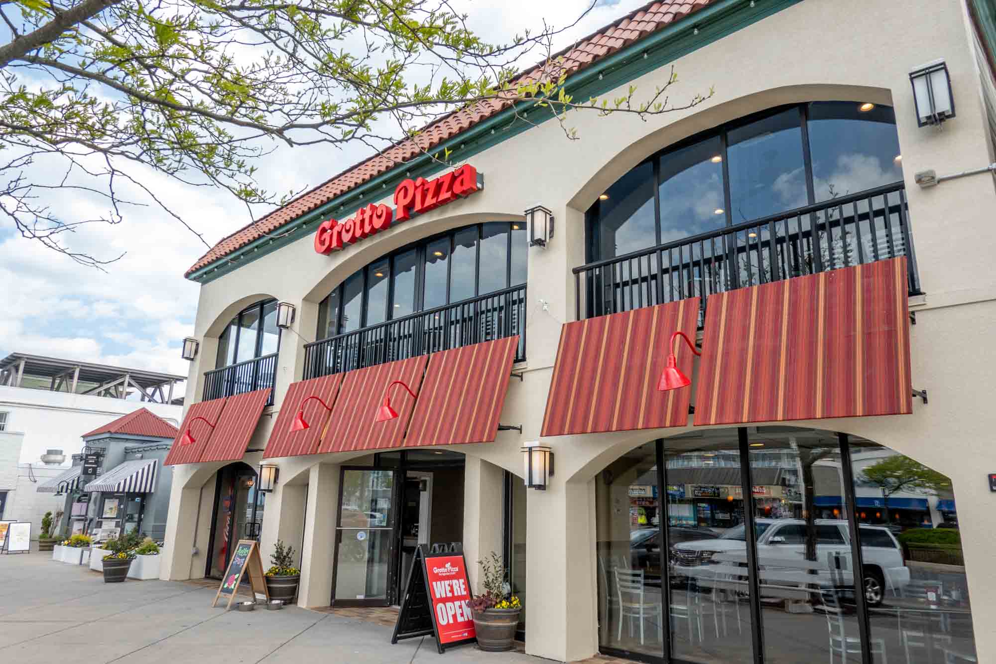 Exterior of a restaurant with red awnings and a sign for "Grotto Pizza"