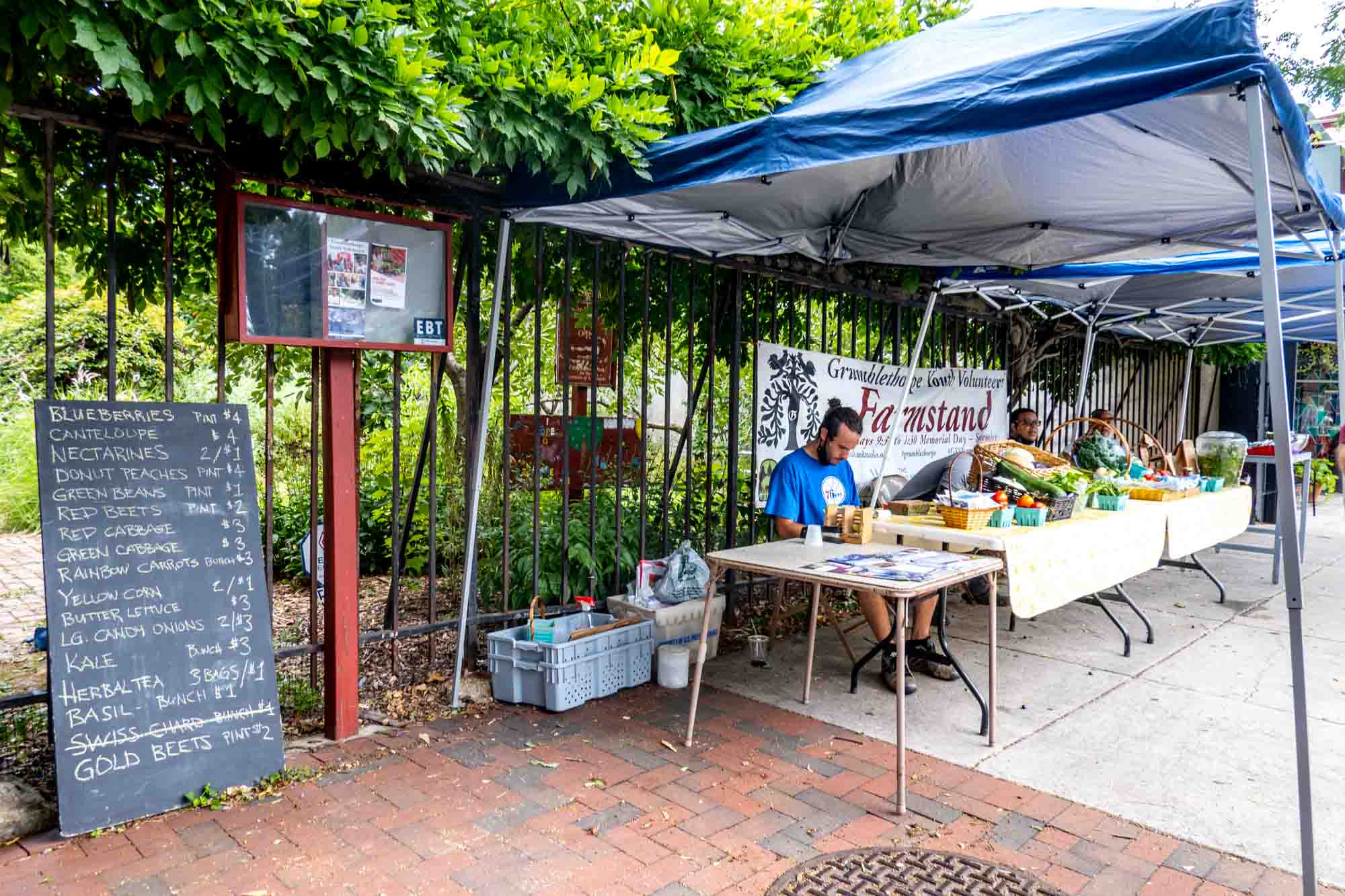 Sign listing fresh produce available at a community farmstand in Philly