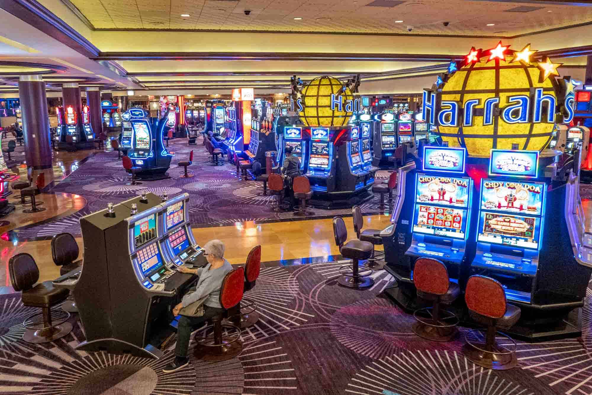 Casino filled with slot machines topped with globes labeled "Harrahs"