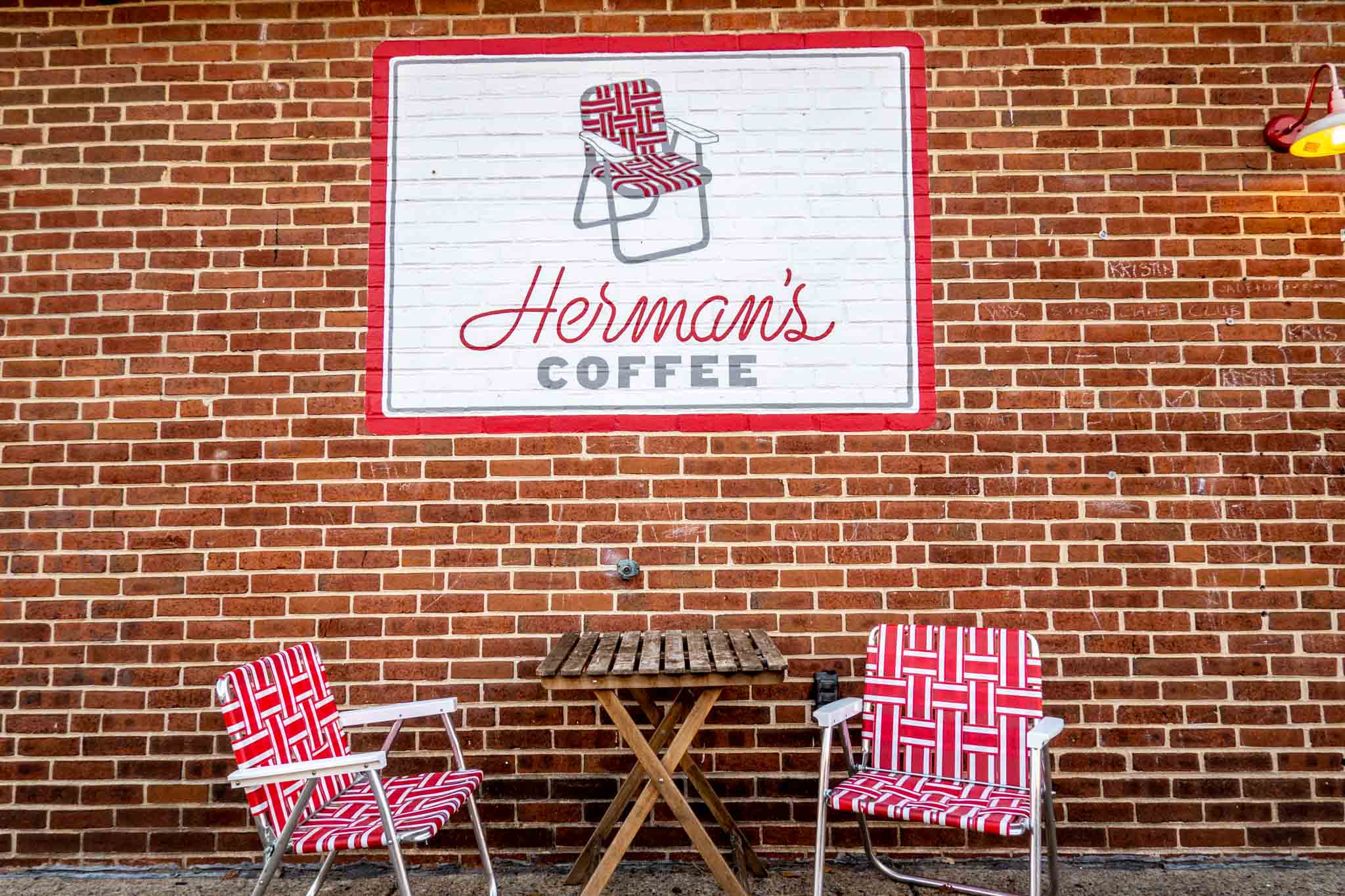 Red lawn chairs under sign for "Herman's Coffee."