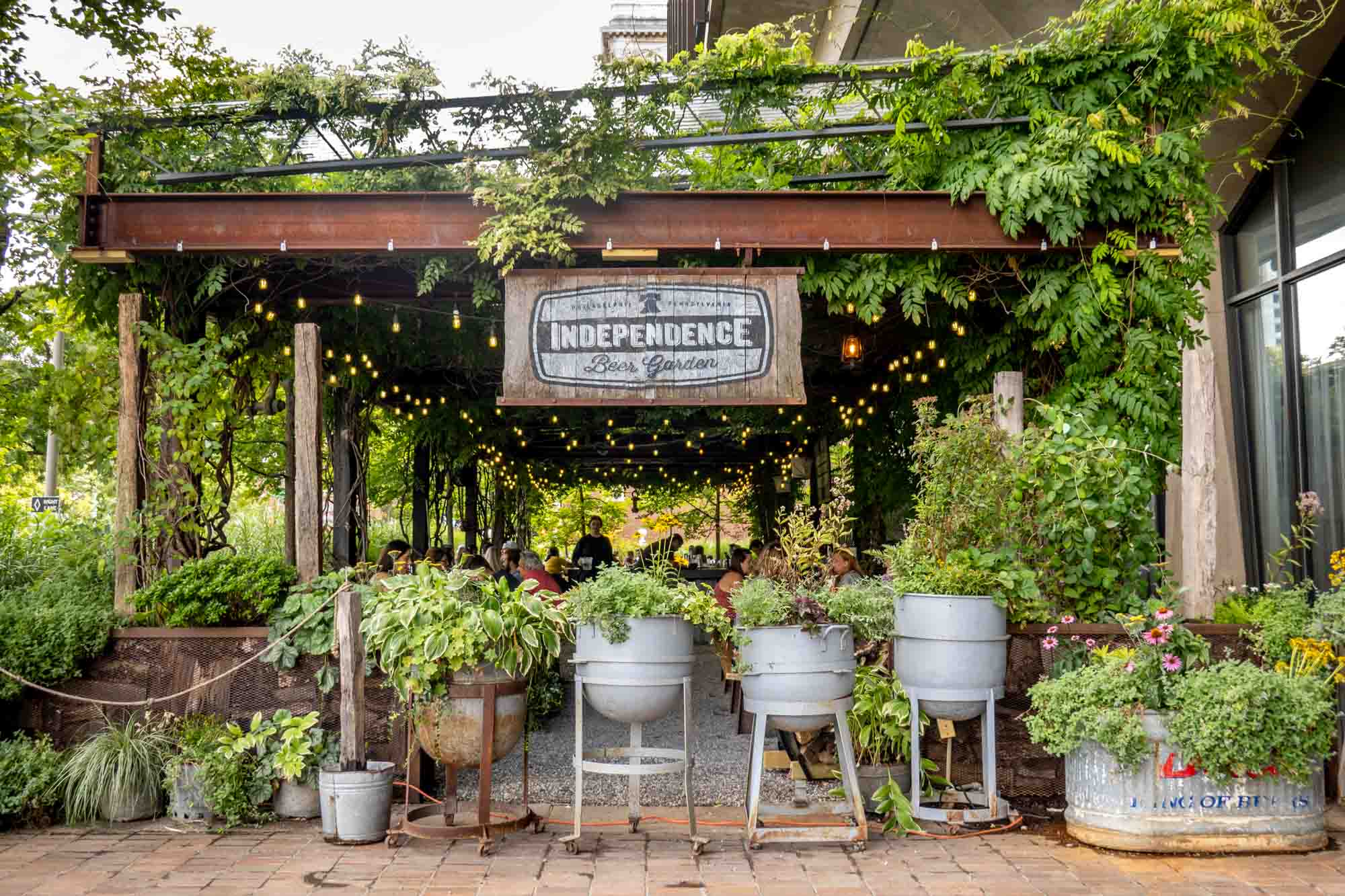 Outdoor seating area filled with plants and a sign: Independence Beer Garden