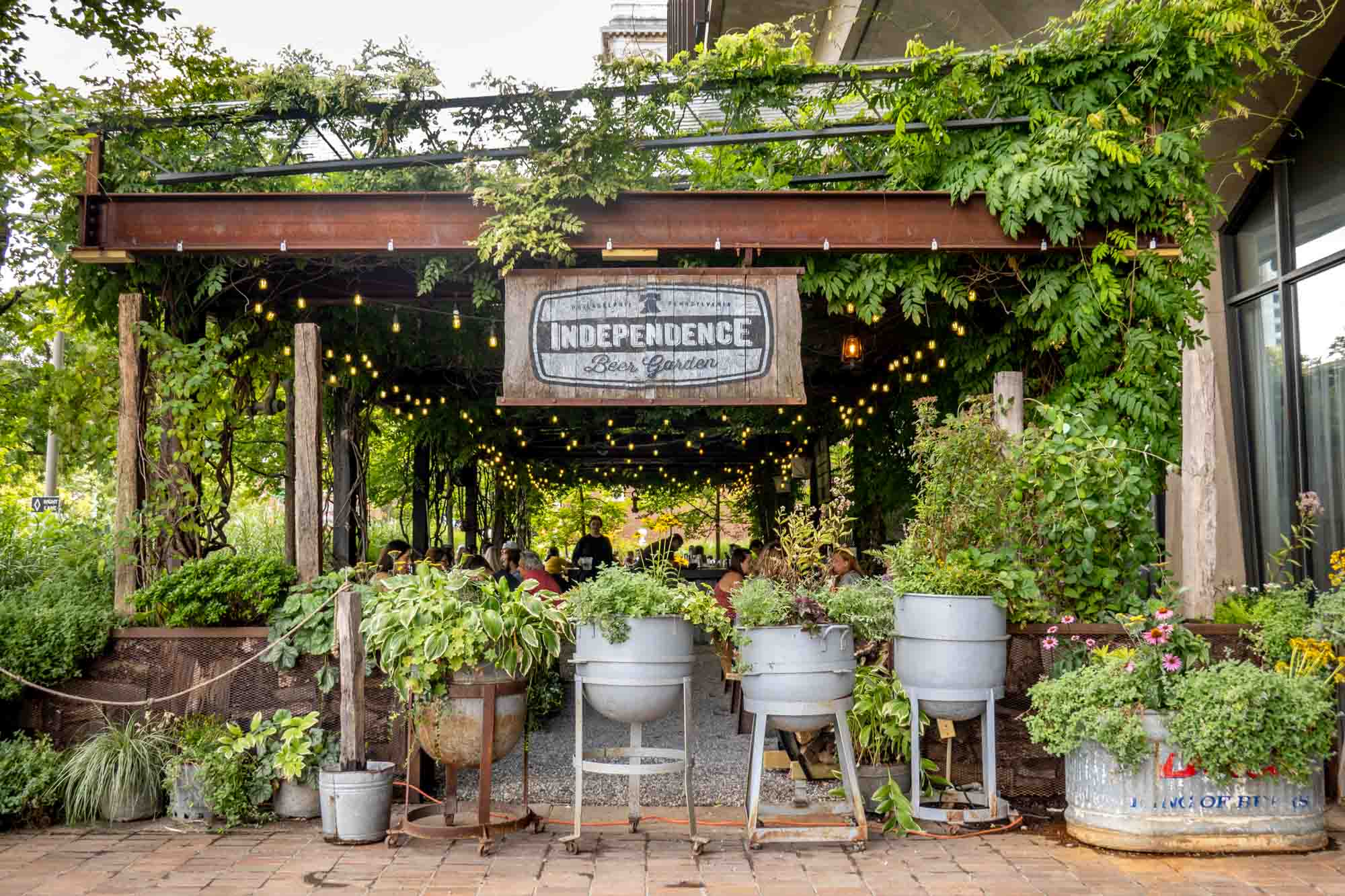 Wood and metal structure covered with plants and a sign for "Independence Beer Garden"