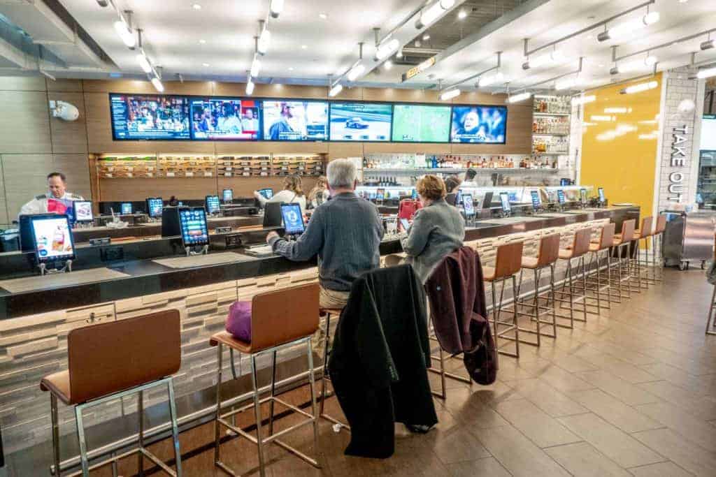 People sitting at a bar at Philadelphia airport with lots of TV screens