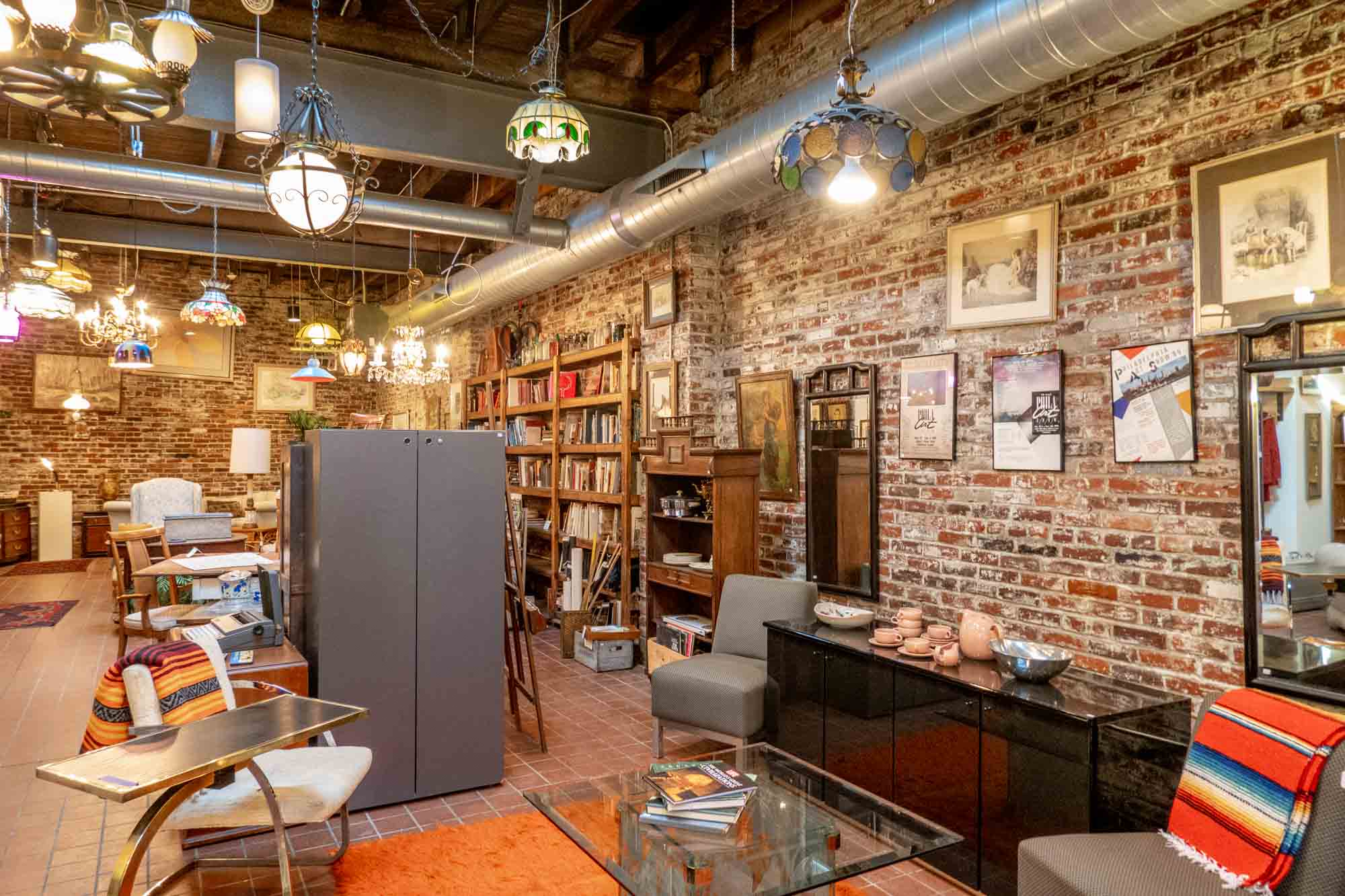 Furniture for sale in a thrift shop room with exposed brick walls