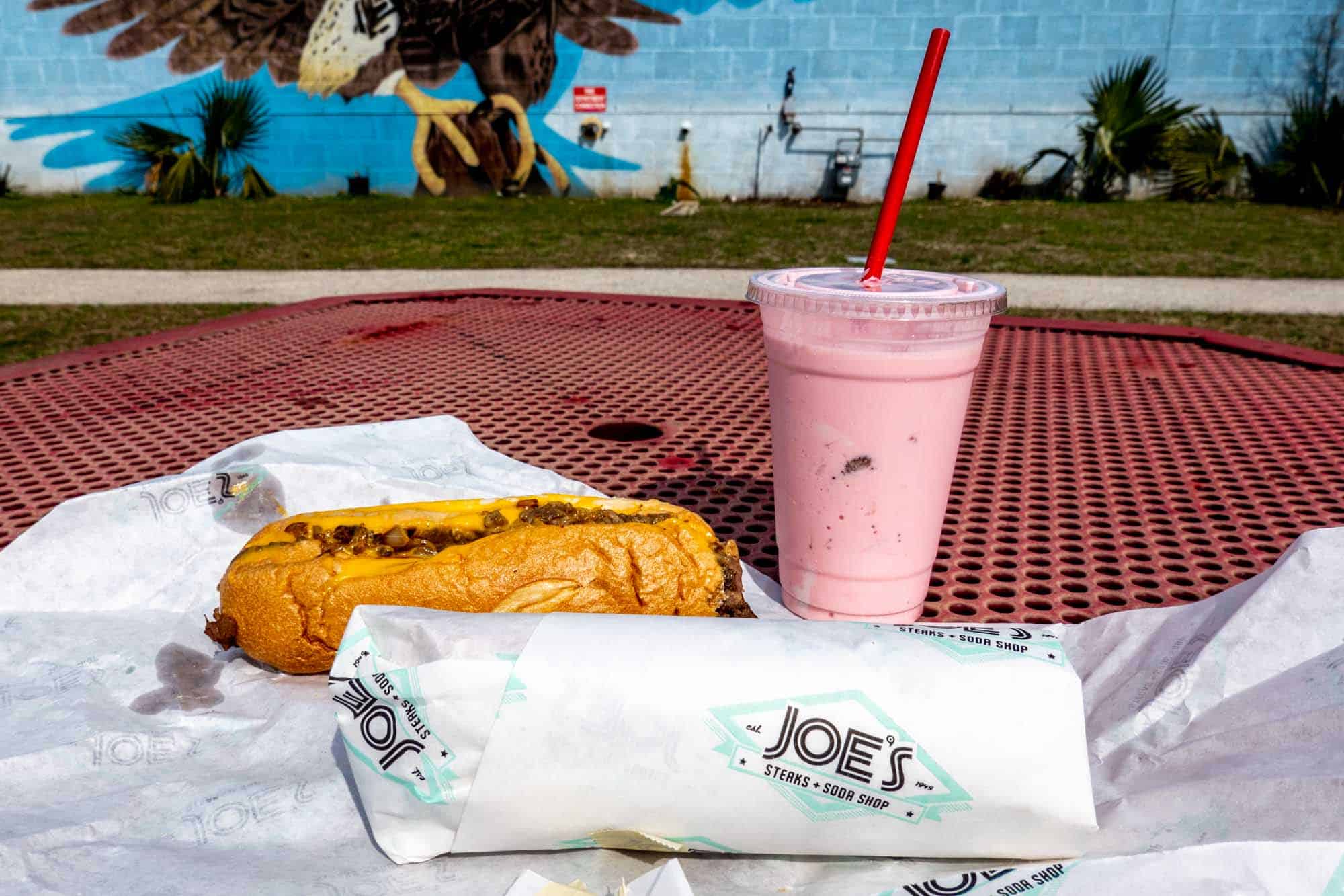 Sandwich and milkshake on a picnic table.