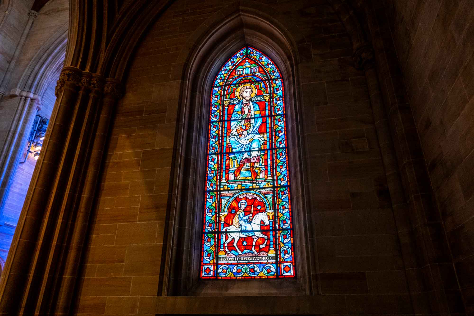 Stained-glass window depicting John the Apostle and a rider on a white horse.