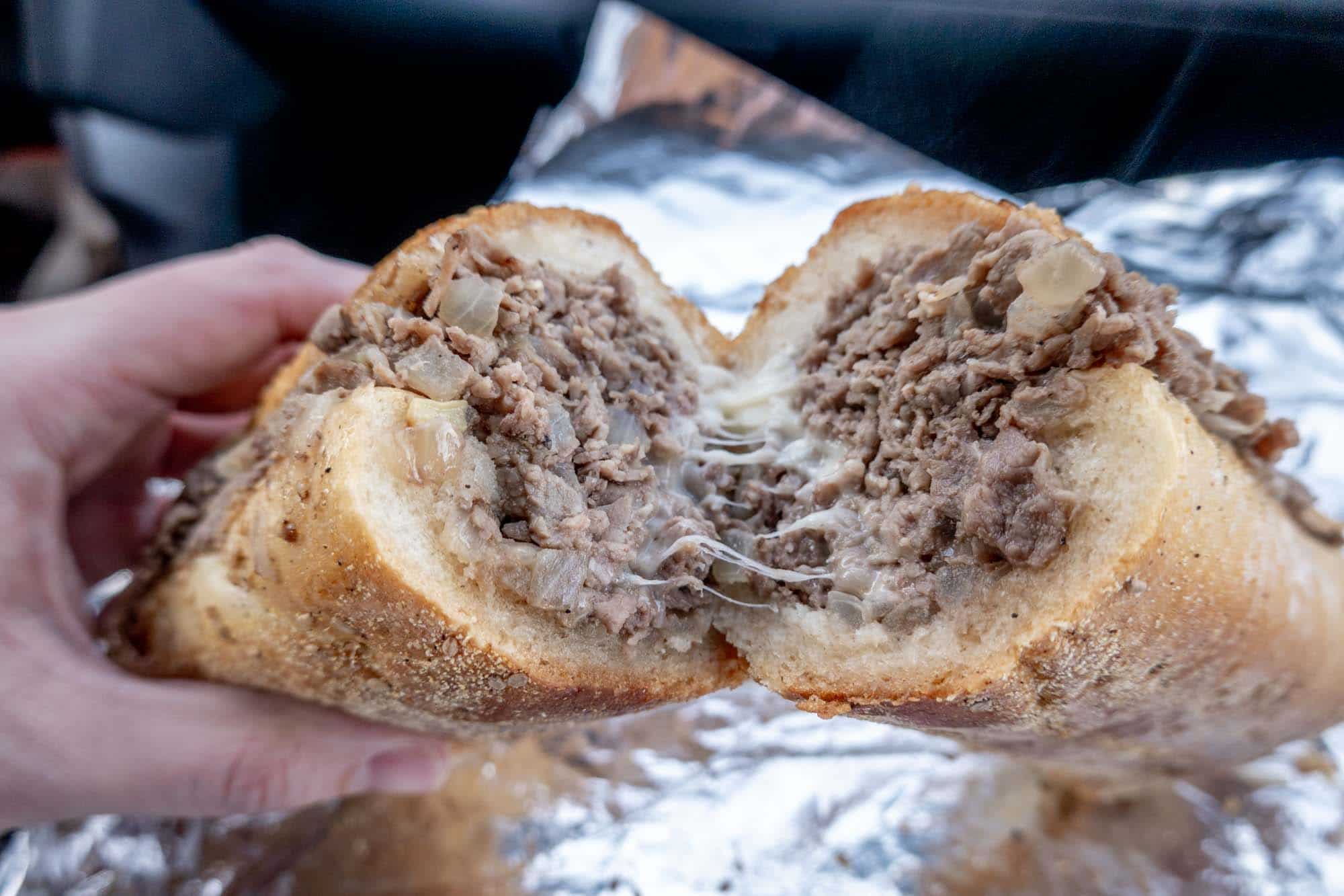 Cheesy steak sandwich cut in half.