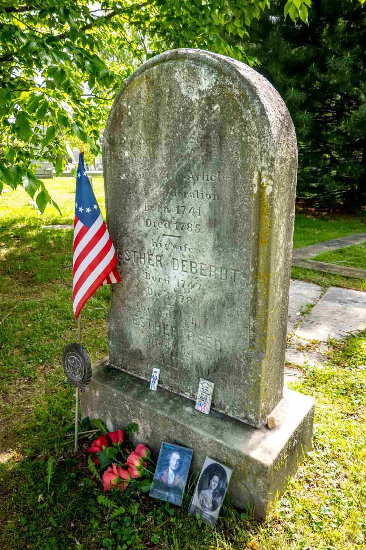 Headstone for Joseph Reed and family decorated with photos and a Colonial flag