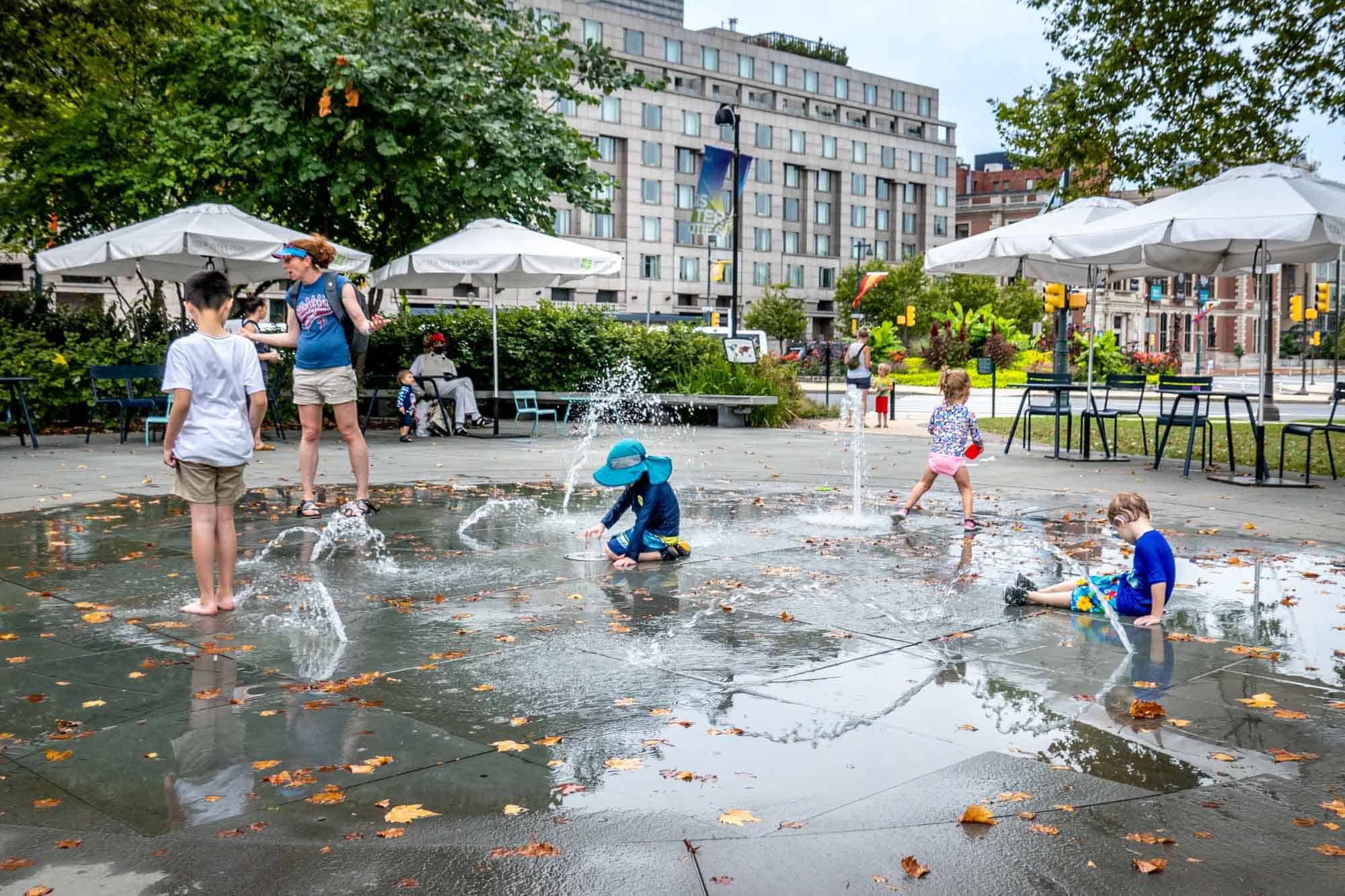 Kids playing in fountains in a park.