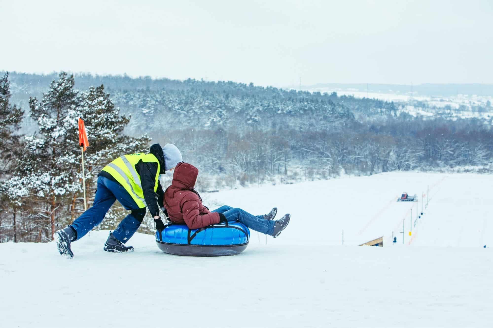 Child pushing another child on an inner tube on snow