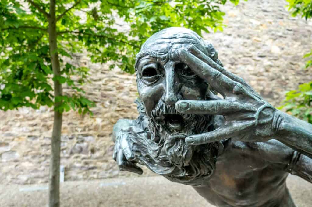 Sculpture of a man looking through his fingers in the sculpture garden of Michener Art Museum