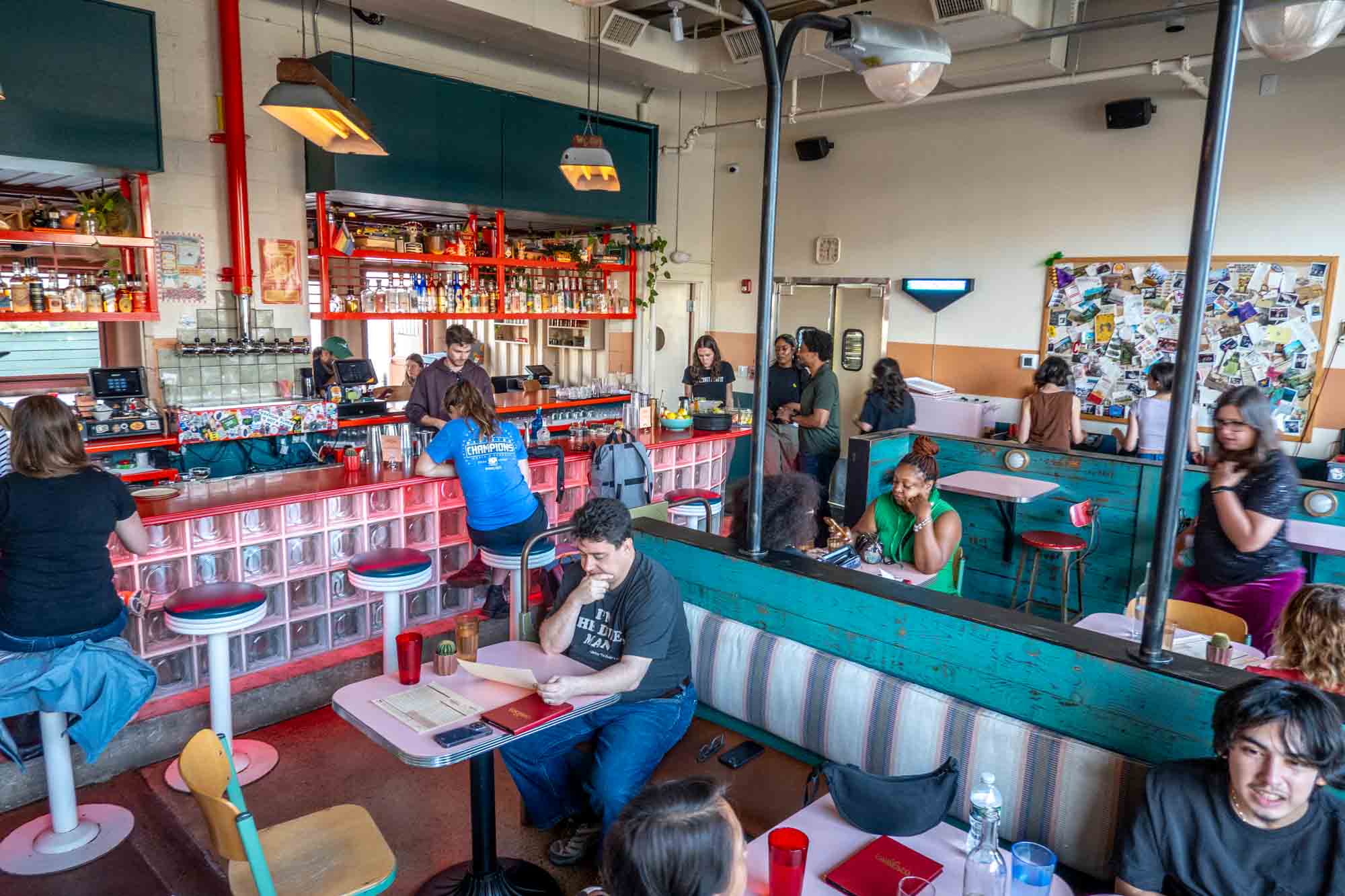 People in a restaurant dining room with a bar on the left side.