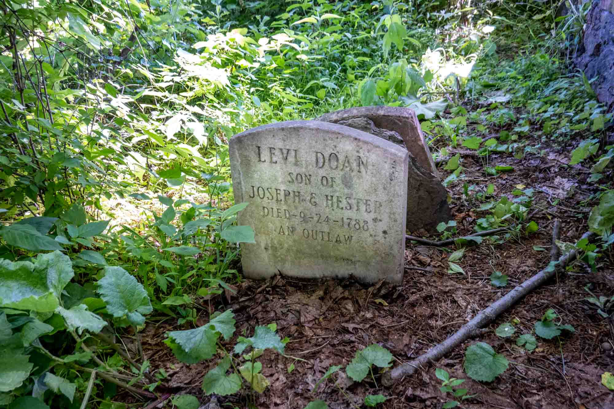 Old gravestone among weeds: Levi Doan, Son of Joseph & Hester, Died 9-24-1788, an outlaw.