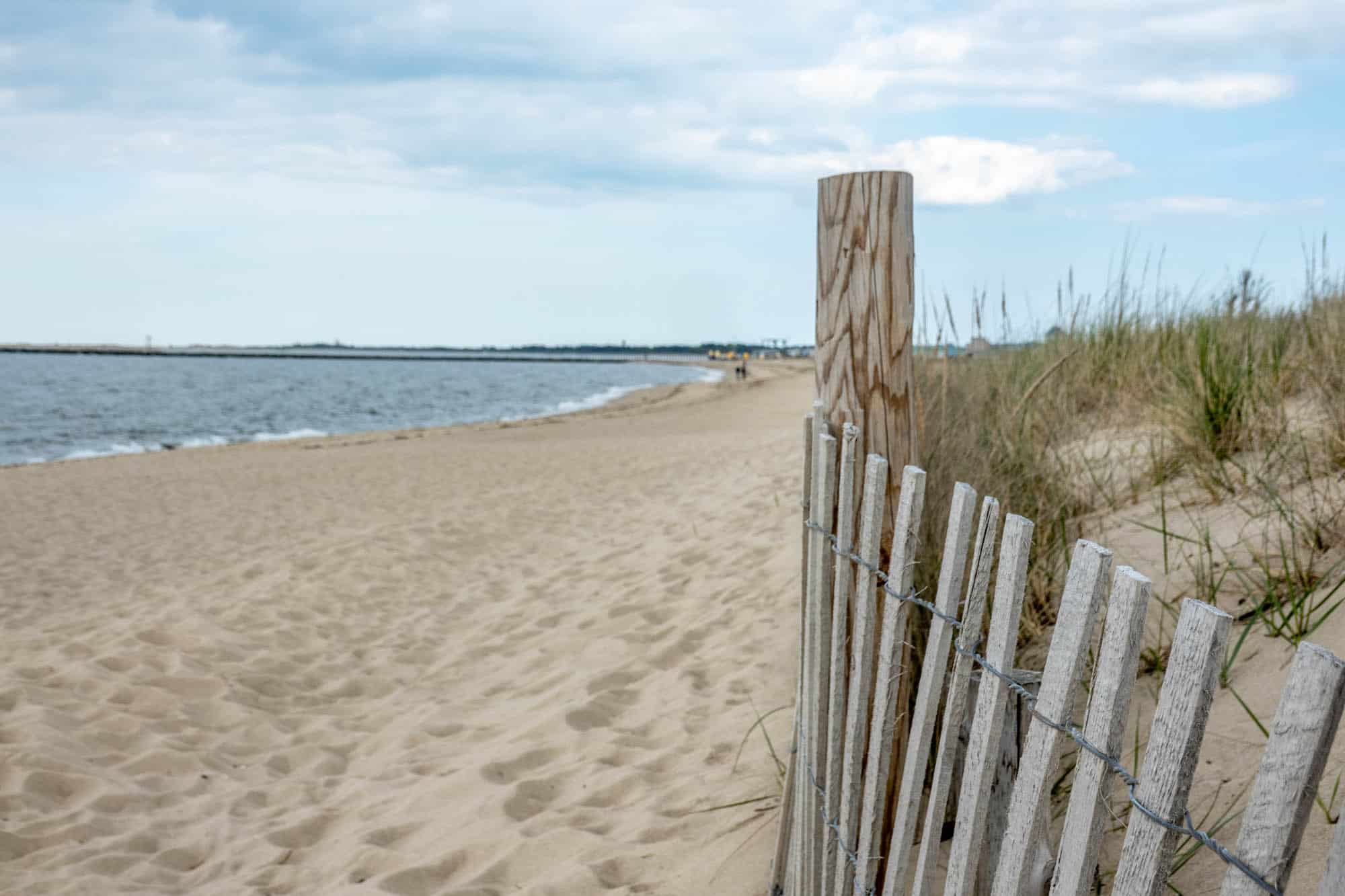 Wooden fence running along a sand dune on a beach.