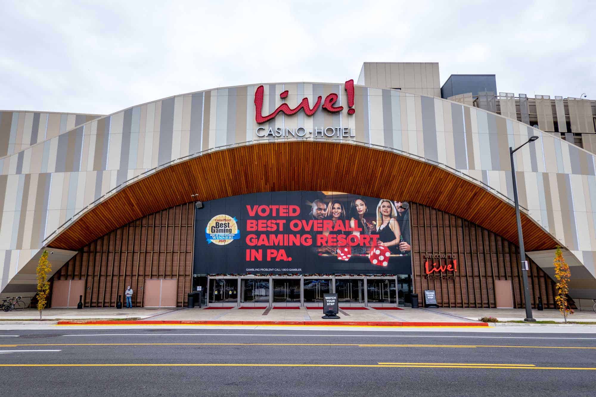 Large building with an arched entryway and a sign for "Live! Casino Hotel" above an advertisement announcing "Voted Best Overall Gaming Resort in PA."