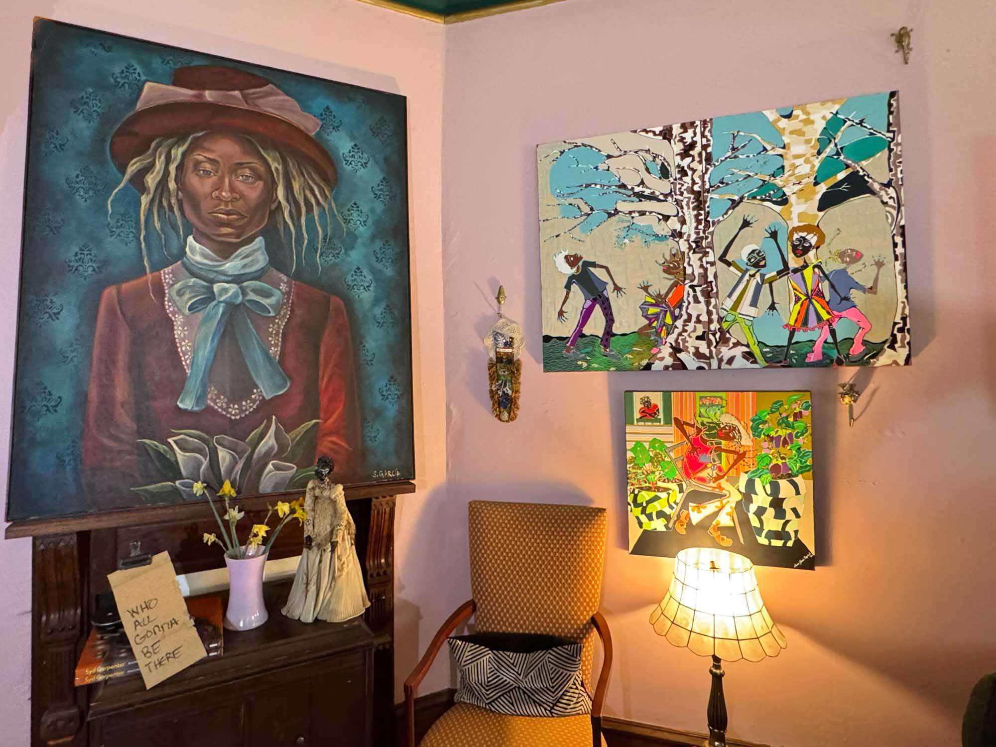 Living room with several paintings, a chair, and sculptures.