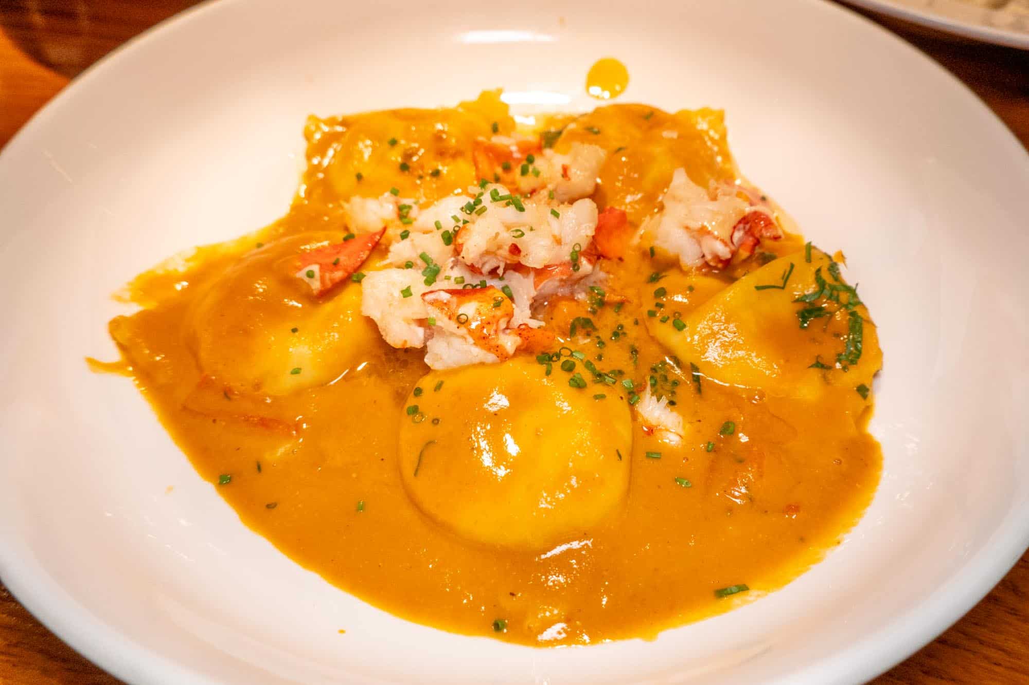 Bowl of ravioli topped with sauce and crab meat.