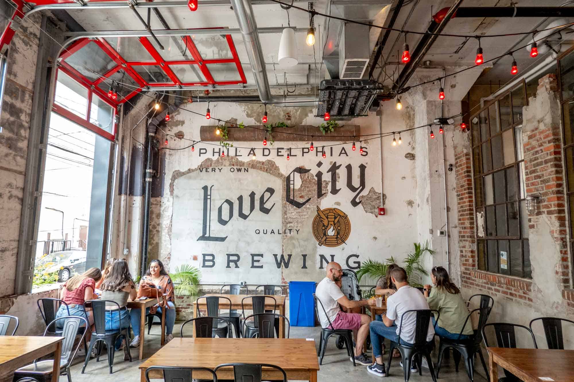 Mural saying "Philadelphia's very own Love City quality brewing" with people at tables