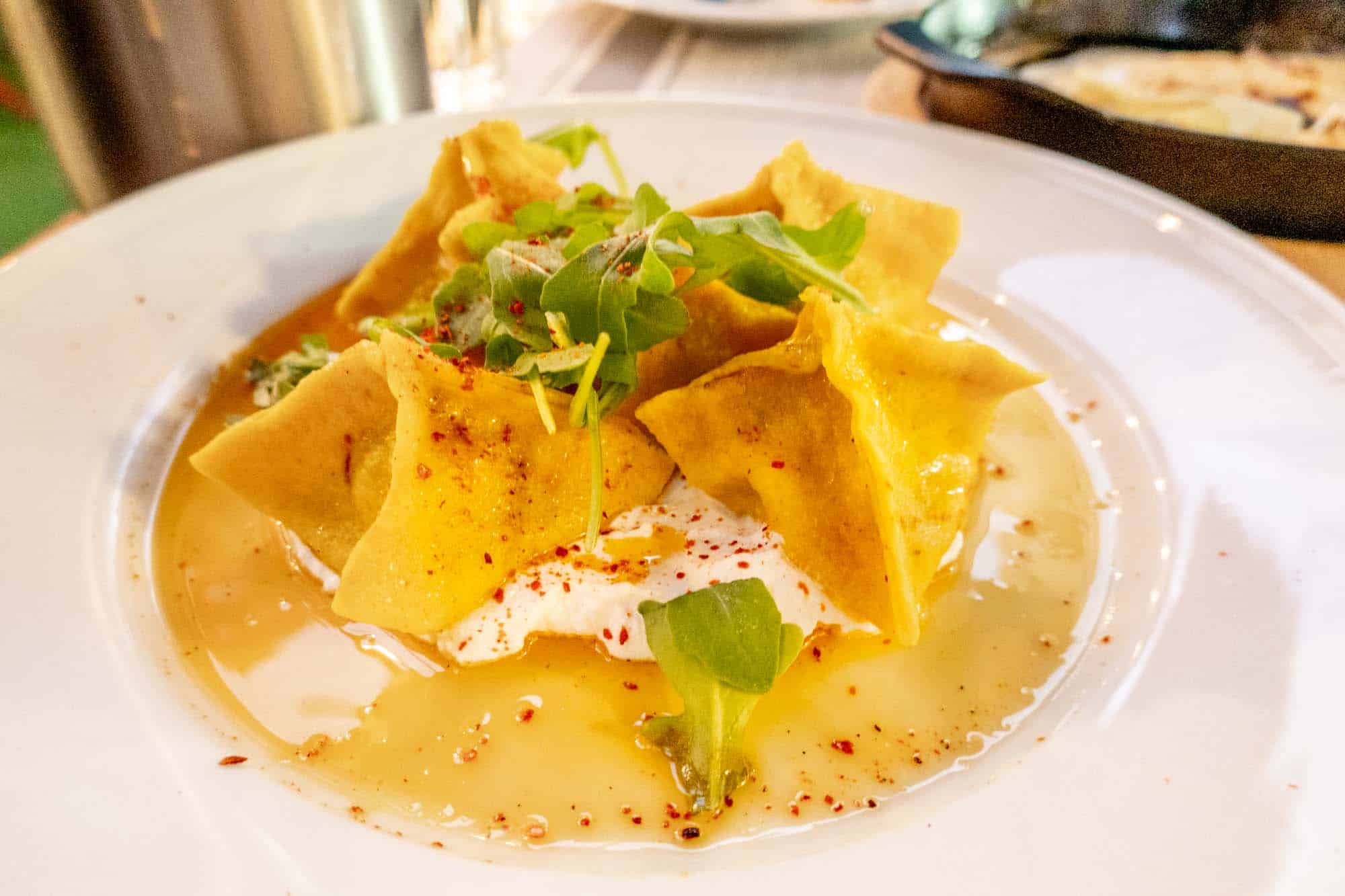 Dumplings in bowl with broth and labneh.