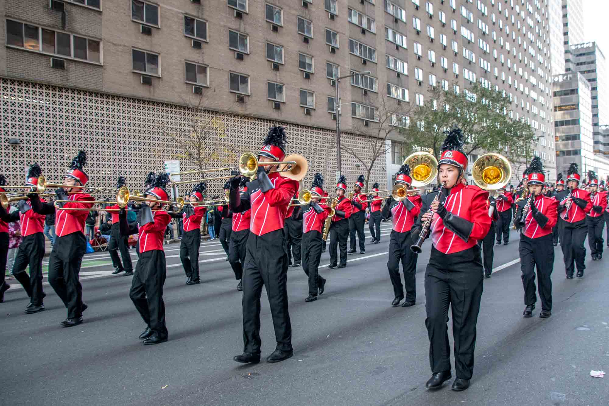 Marching band in parade with red and black uniforms