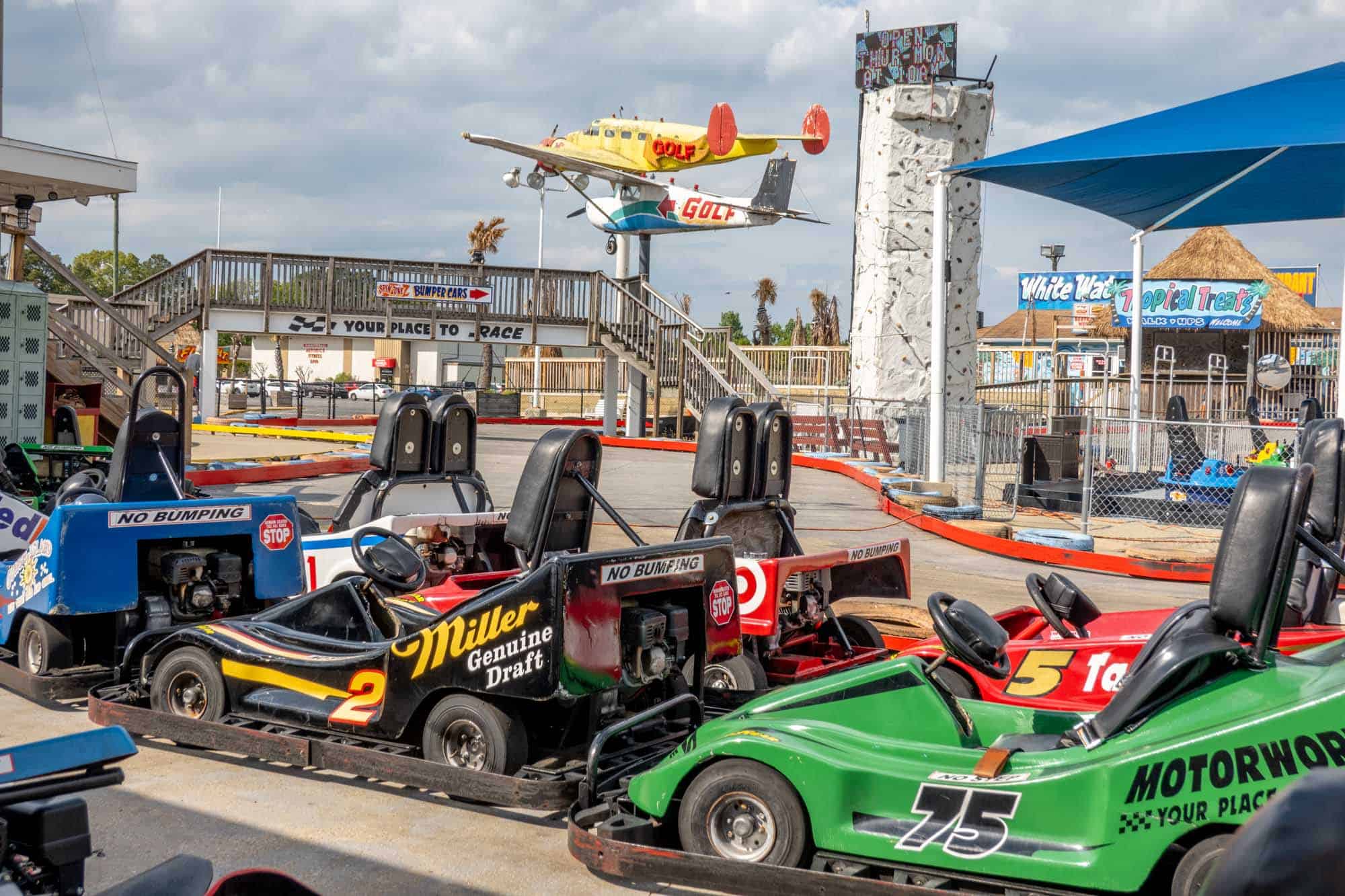 Go karts stopped on a tracks with two small planes displayed in the background.