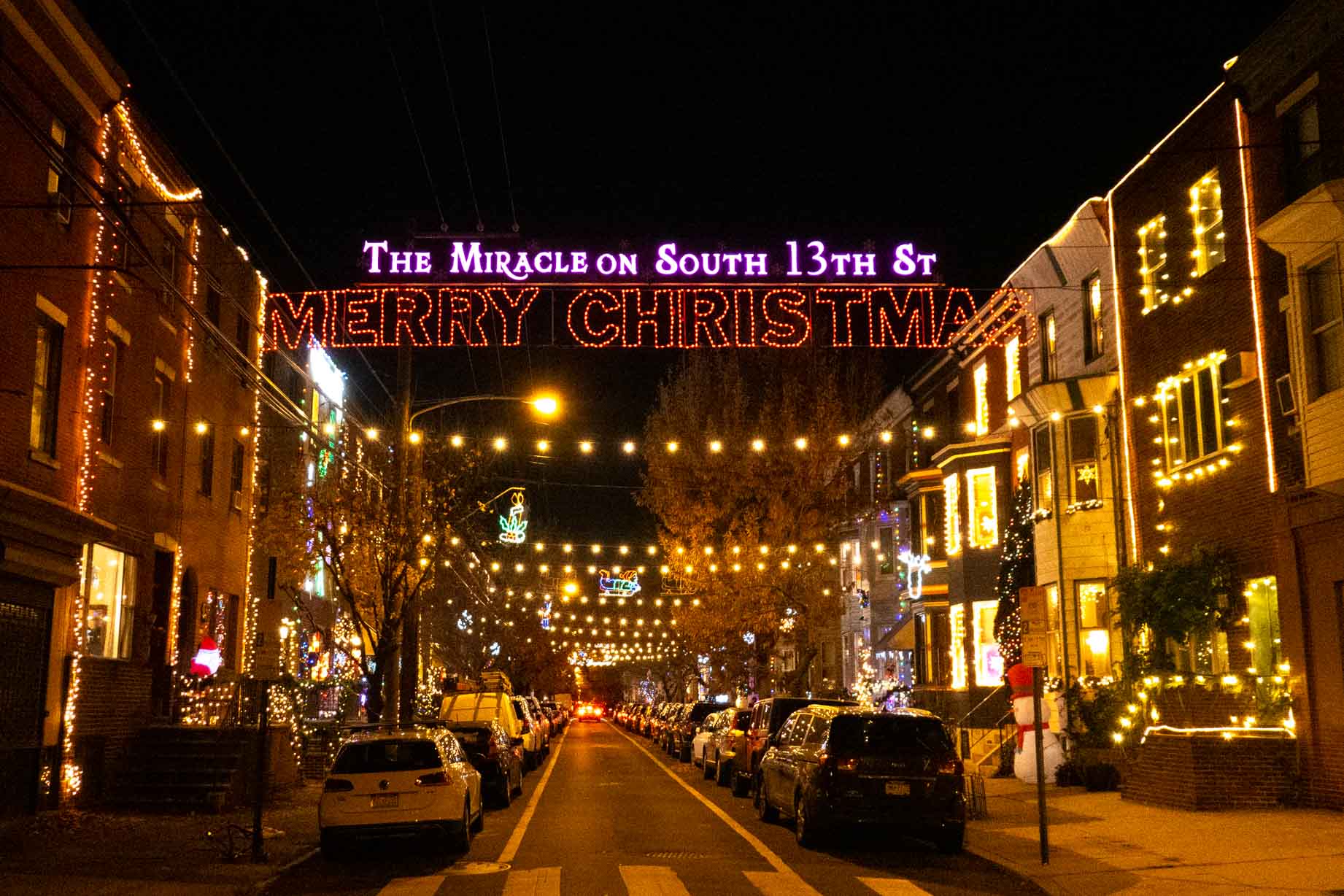 Illuminated sign above street reading "The Miracle on South 13th St Merry Christmas."