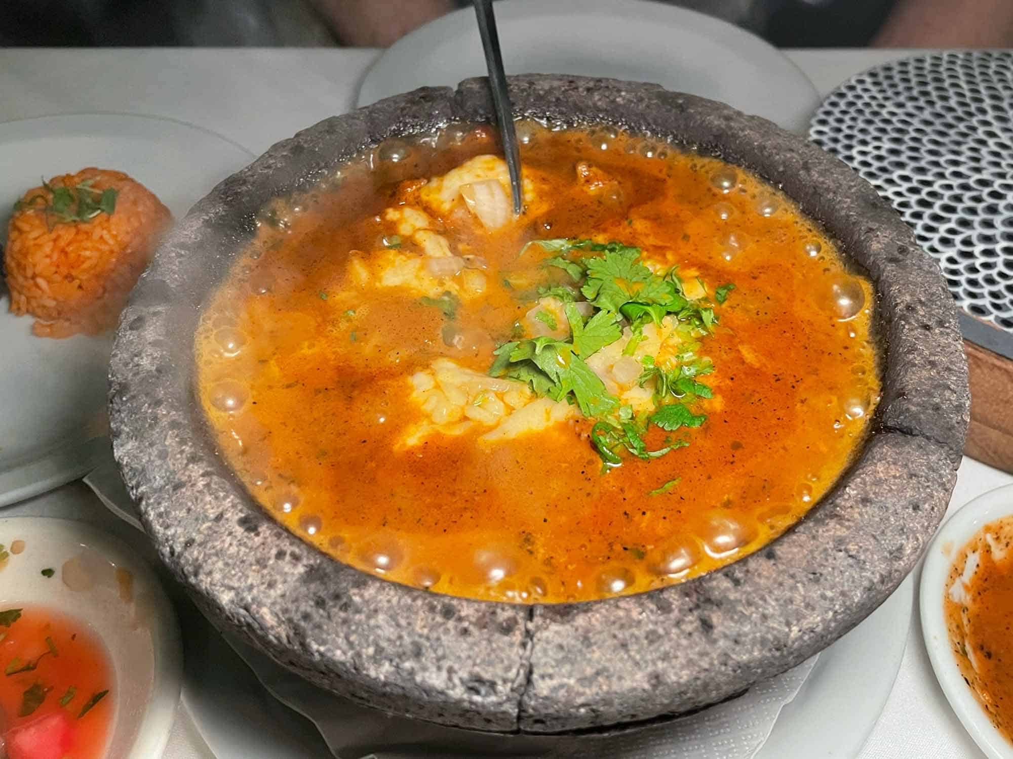 Bubbling Mexican food in a black lava bowl.