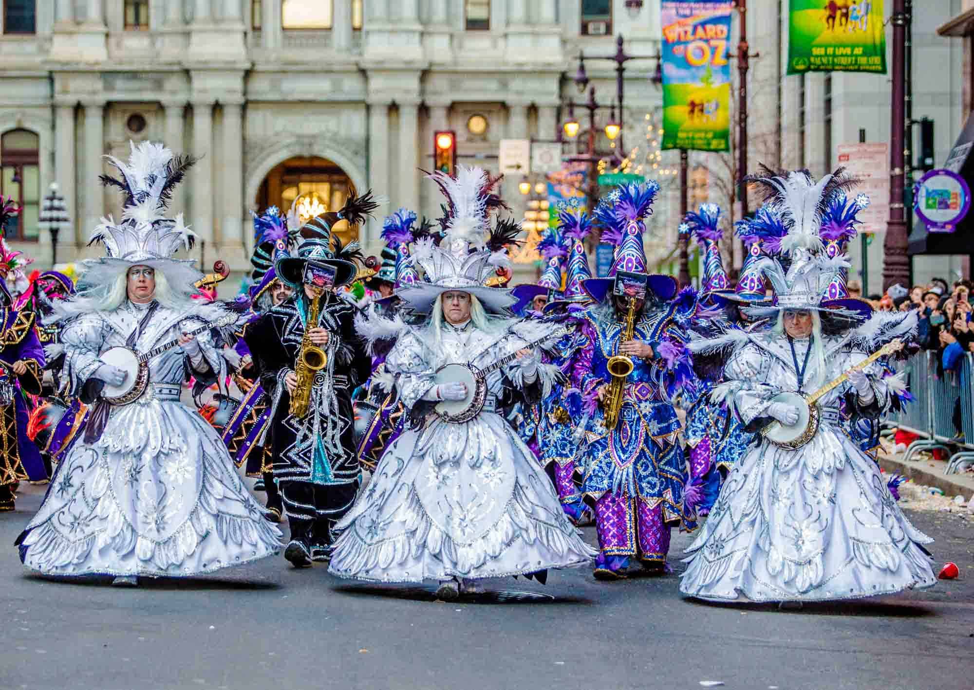 People in elaborate colorful costumes playing instruments in a parade.