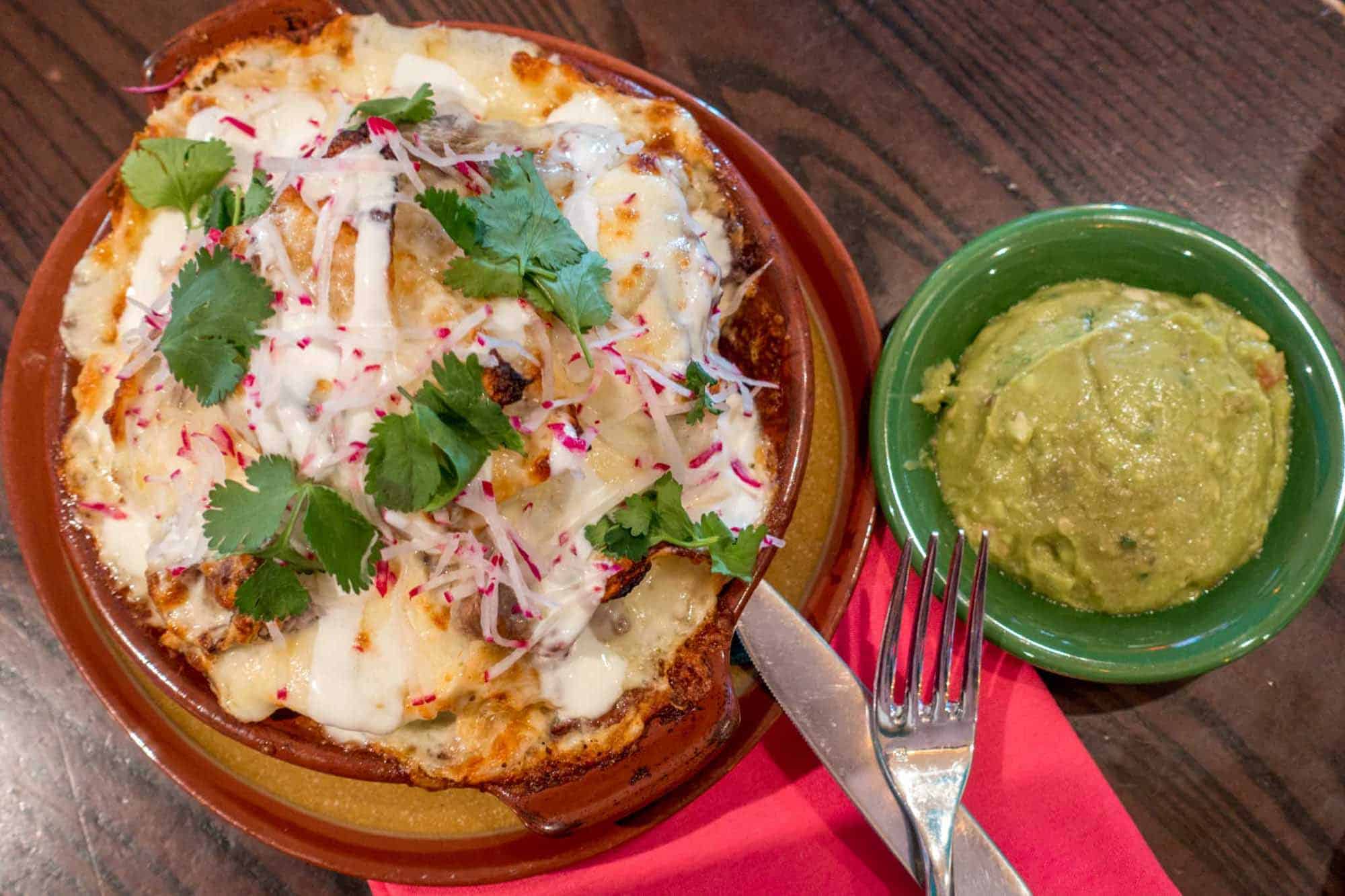 Nachos and guacamole in dishes on a table.