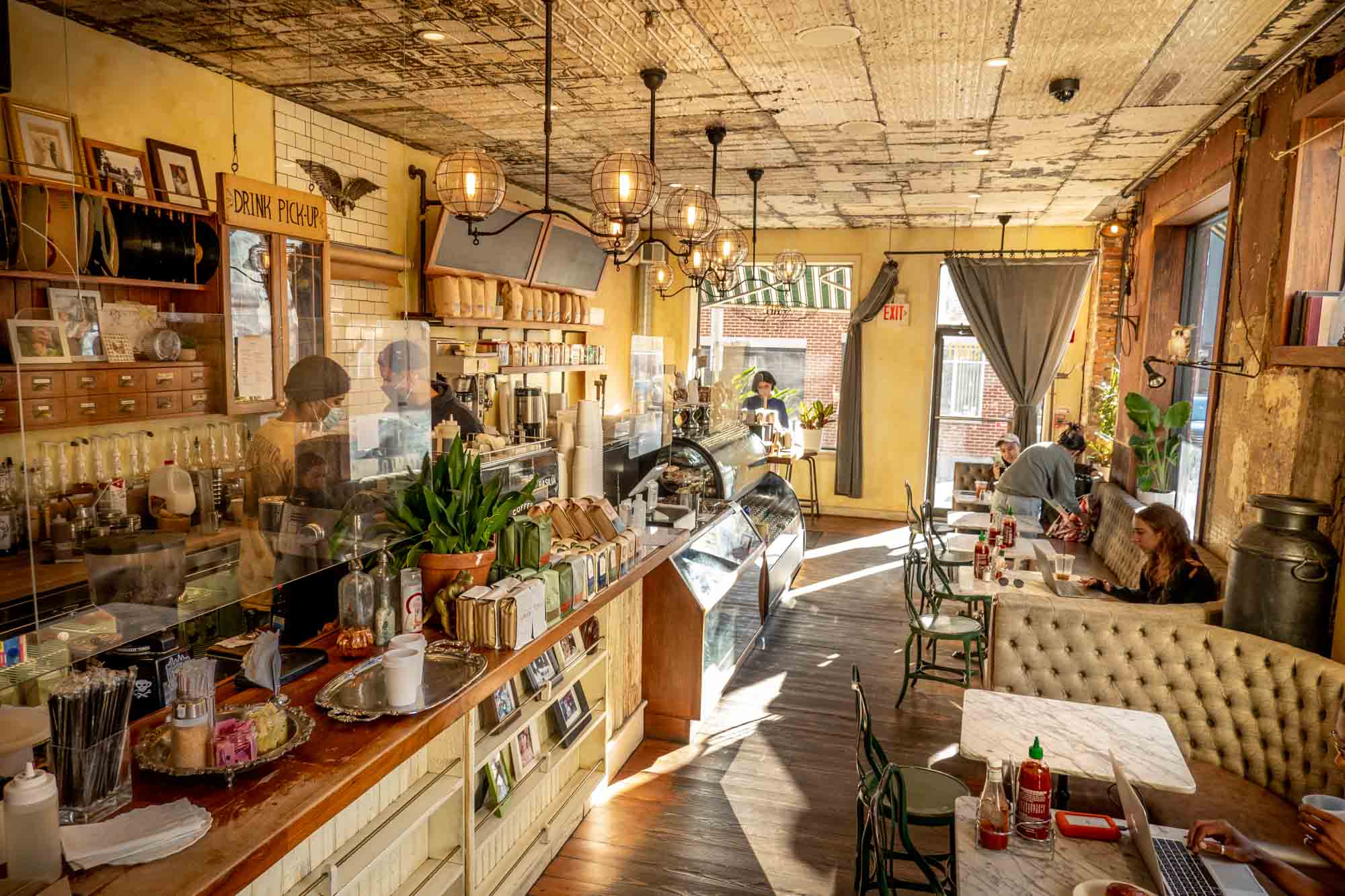 People in a cafe with a coffee bar adjacent to couches, tables, and chairs.