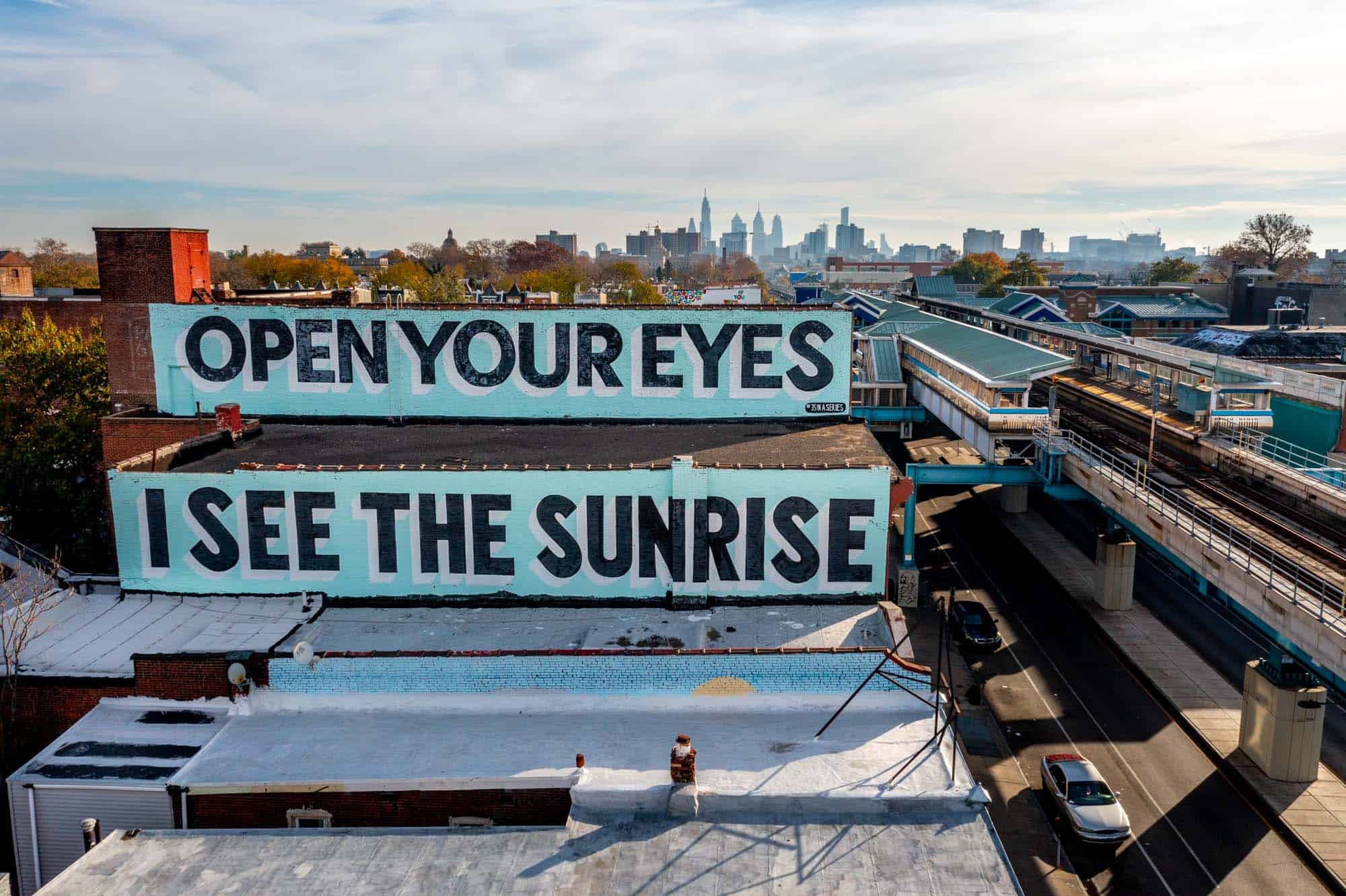 Turquoise mural with the words "Open Your Eyes, I See the Sunrise."