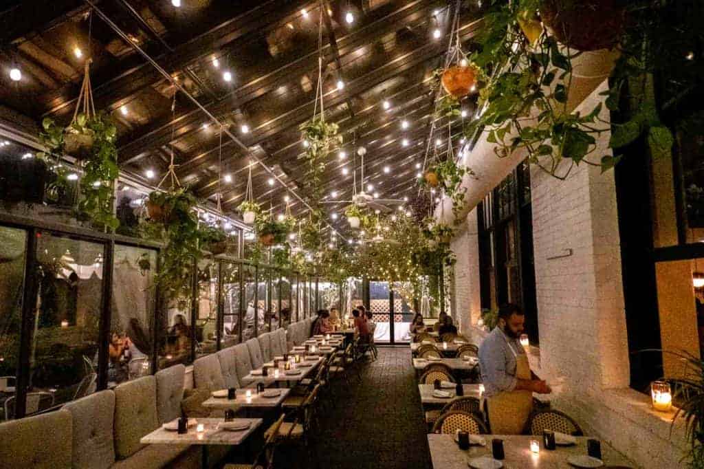 Airy restaurant patio with white brick, white lights, and plants