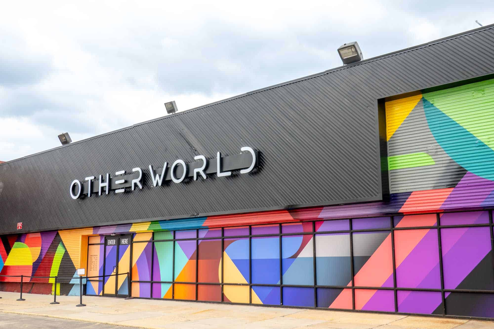Geometric shapes in all the colors of the rainbow under a sign that reads "Otherworld"