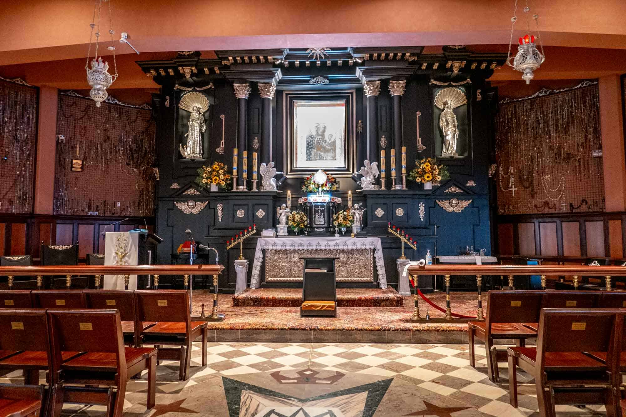 Church altar decorated with candles, flowers, and statues with the image of Mary and baby Jesus.