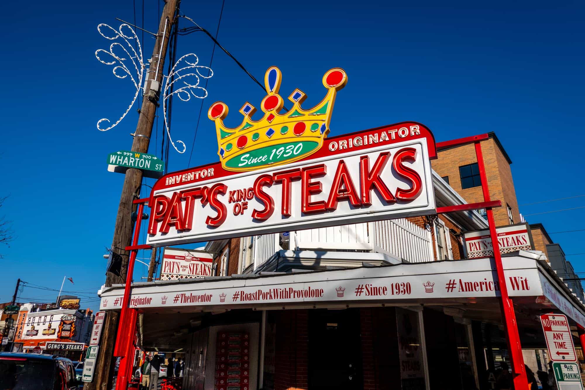 Exterior of a restaurant with a crown-topped sign: "Pat's King of Steaks, Inventor. Originator. Since 1930."