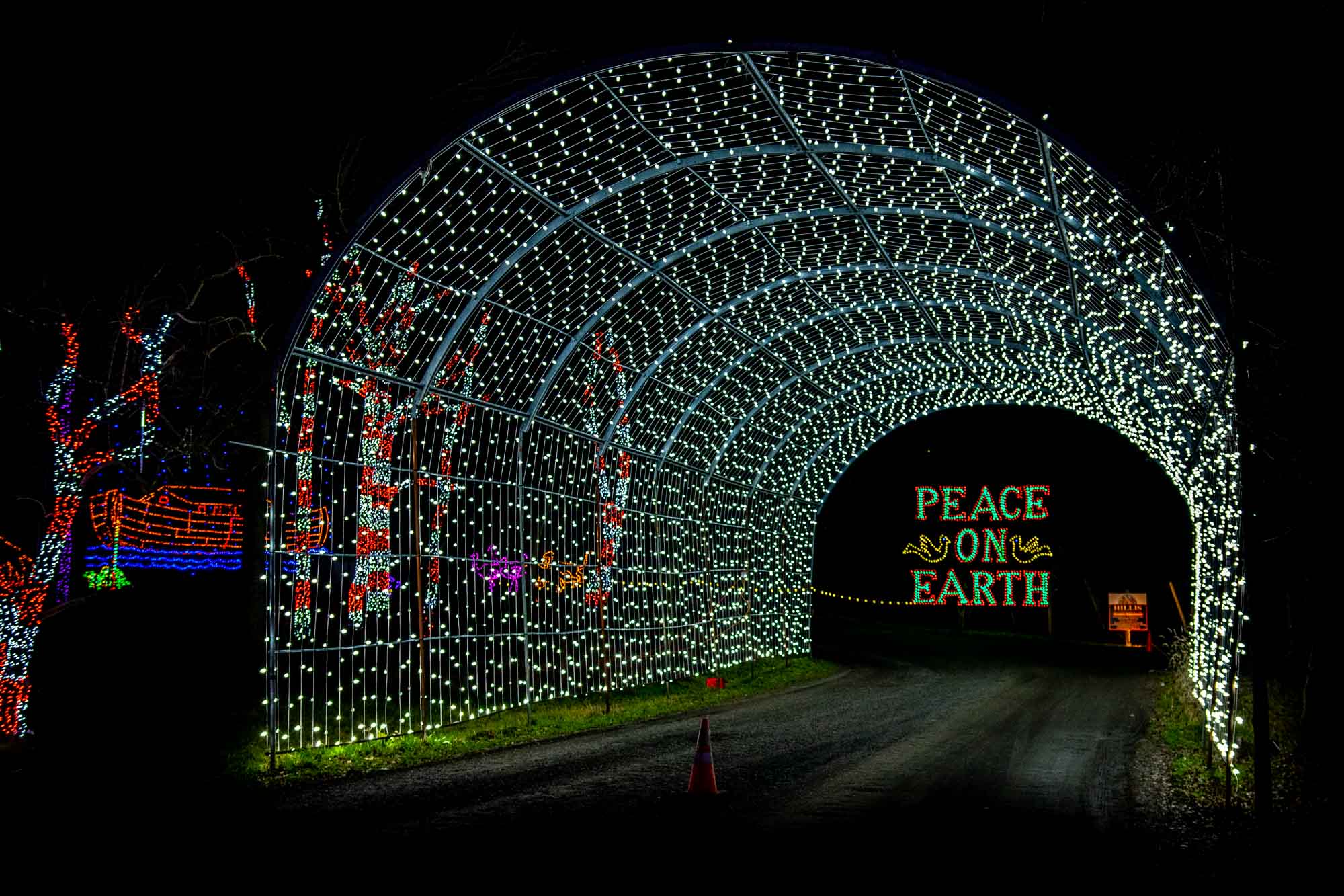 Drive thru tunnel of white lights with a "Peace on Earth" sign at the end