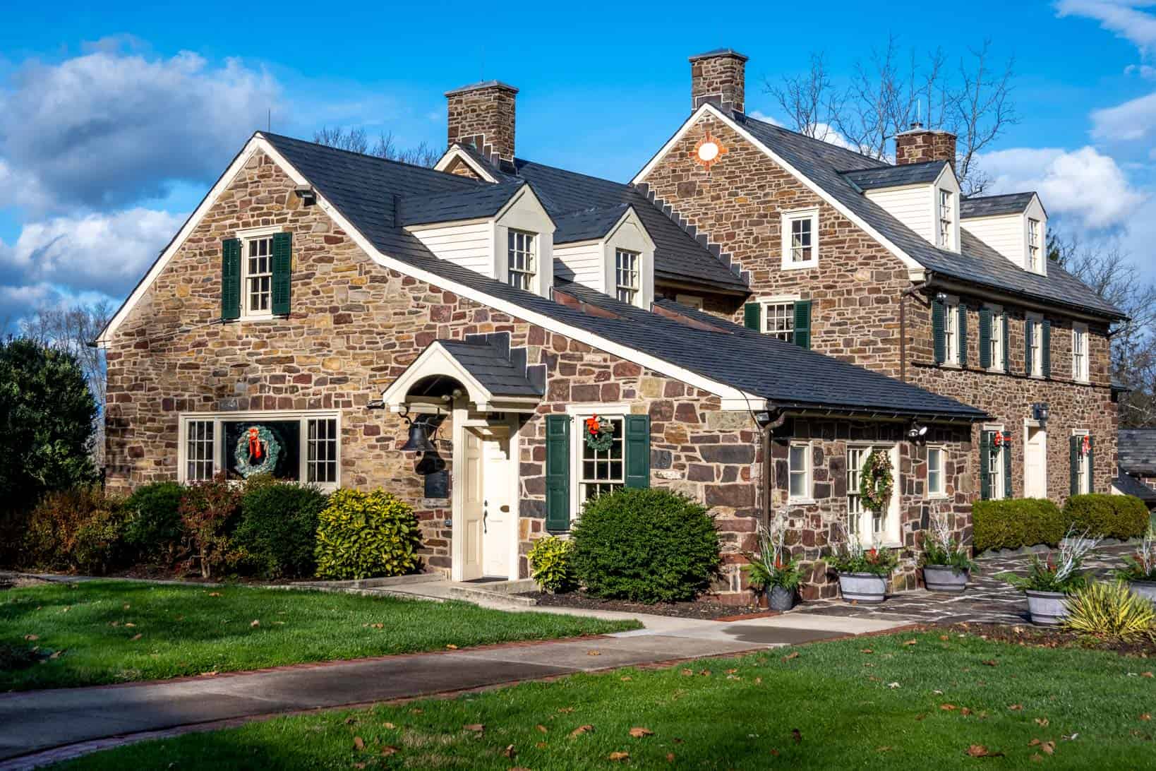 Large stone house with Christmas wreaths on the windows.