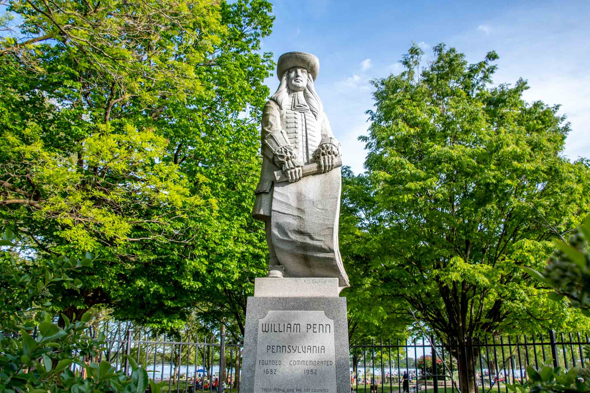 Stone statue of a main in 17th-century dress holding a document on a pedestal that says: "William Penn. Pennsylvania. Founded, 1682. Commemorated, 1982."