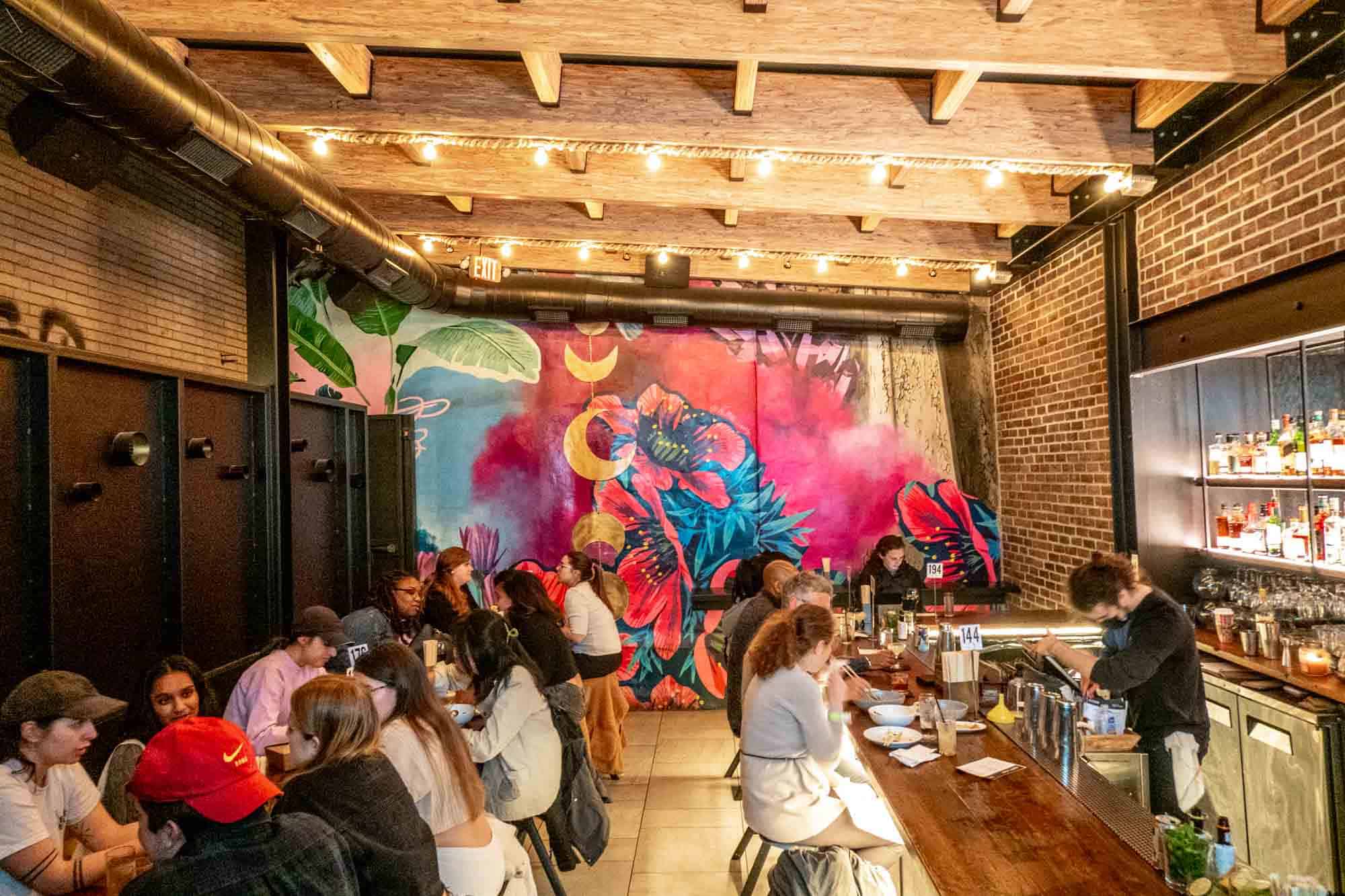 People in Graffiti Bar with a bright, painted wall mural