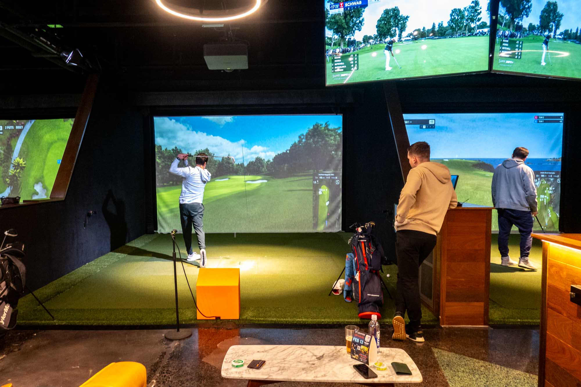 People playing on an indoor golf simulator.