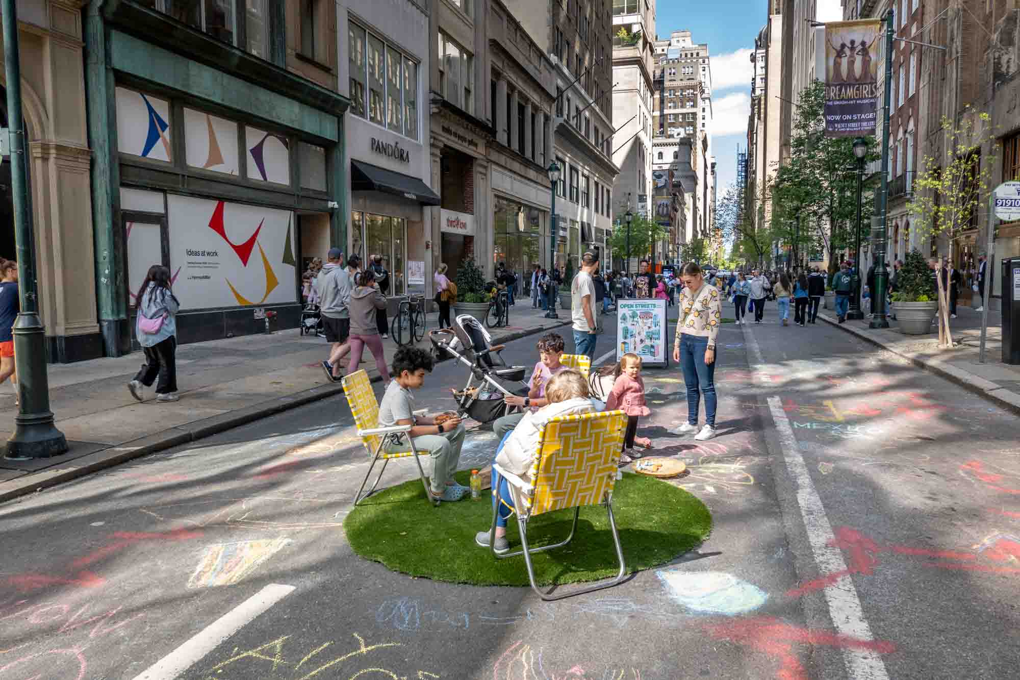People sitting in lawn chairs in the middle of a pedestrianized city street.