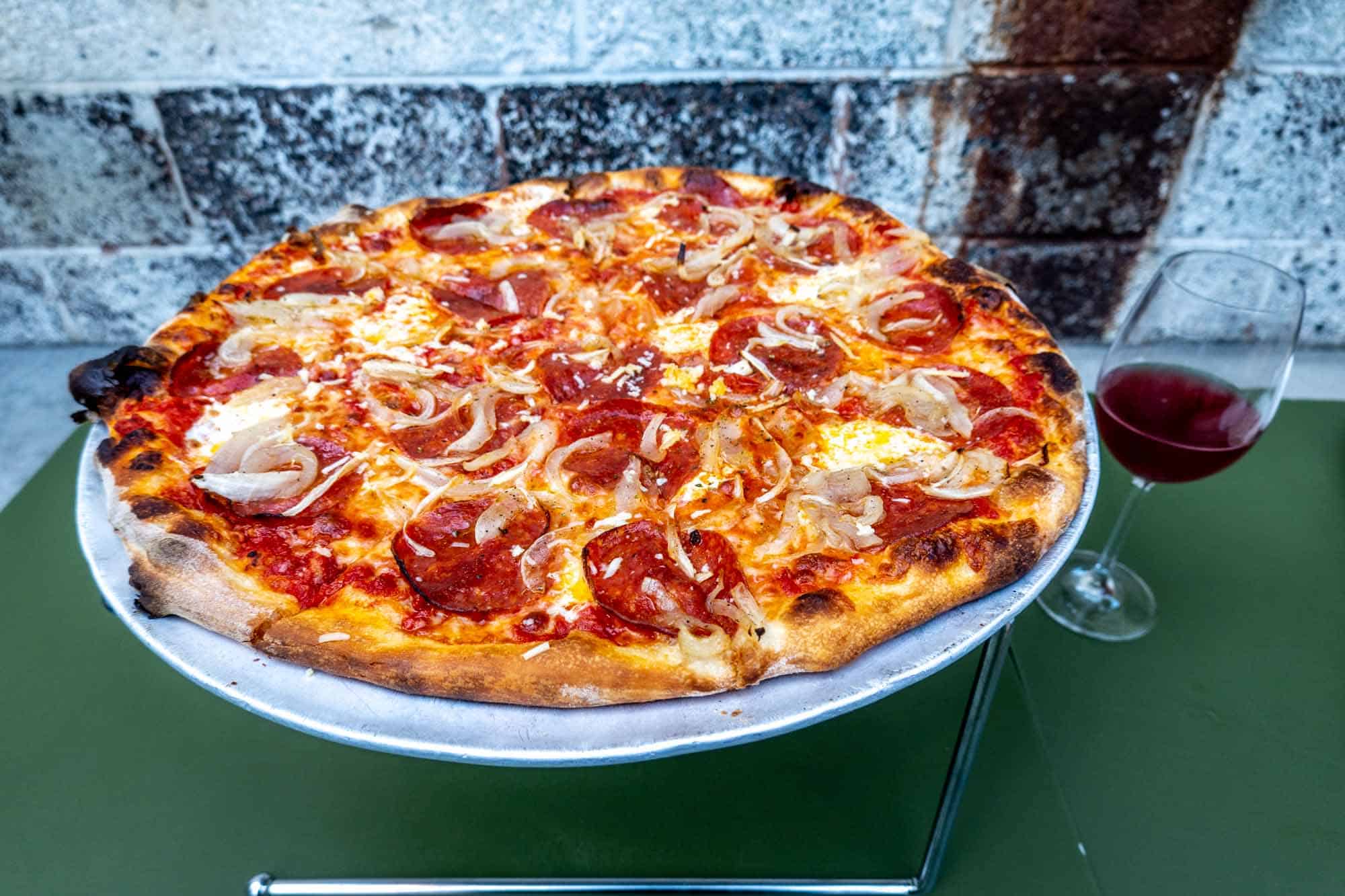 Pepperoni pizza on a pizza stand on a green table.