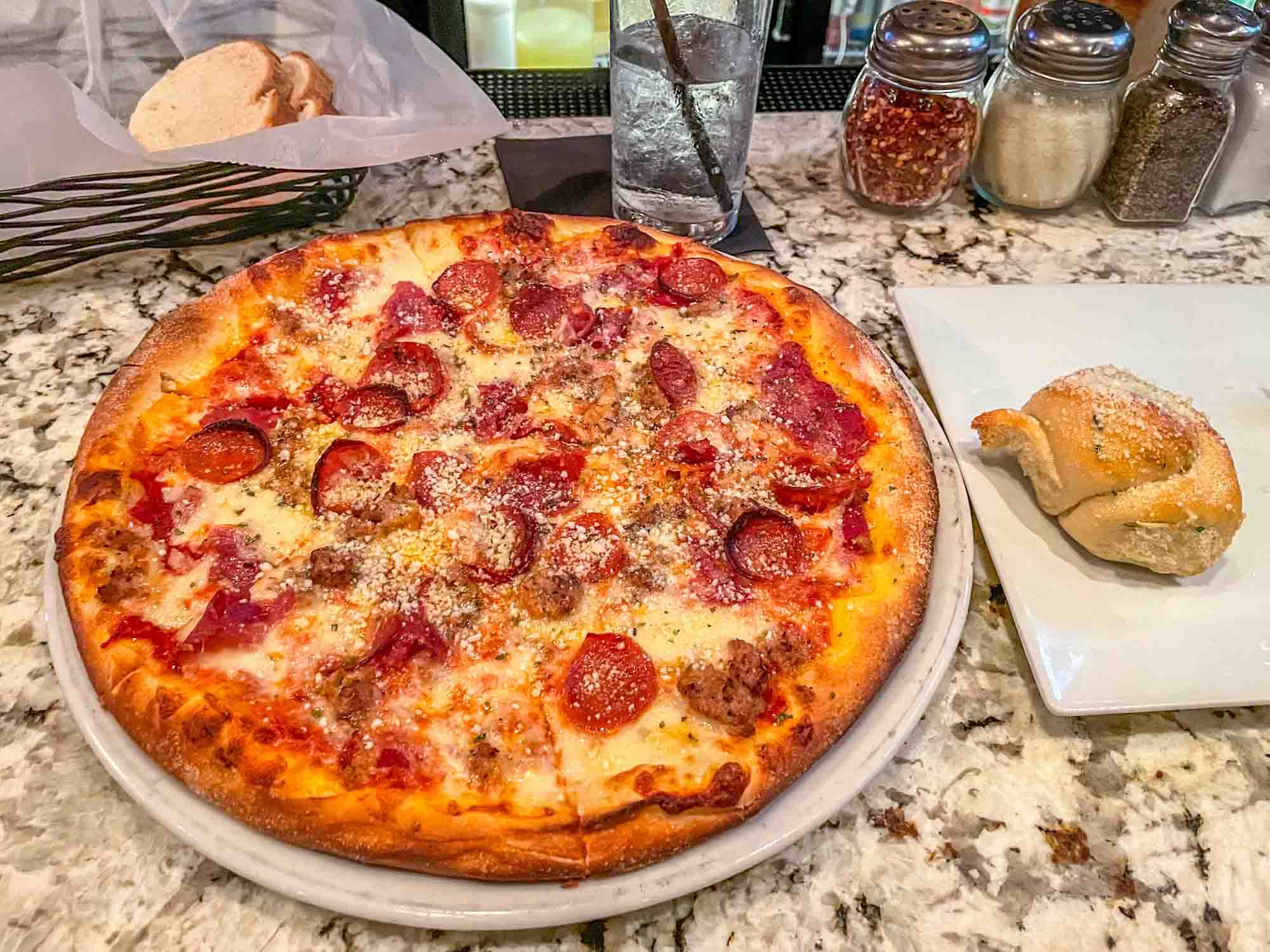 Pepperoni pizza and a garlic knot on a restaurant bar. 