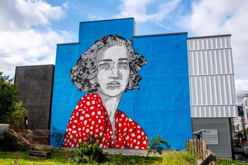 Persistence: mural of a woman in a red polka dot dress with a blue background