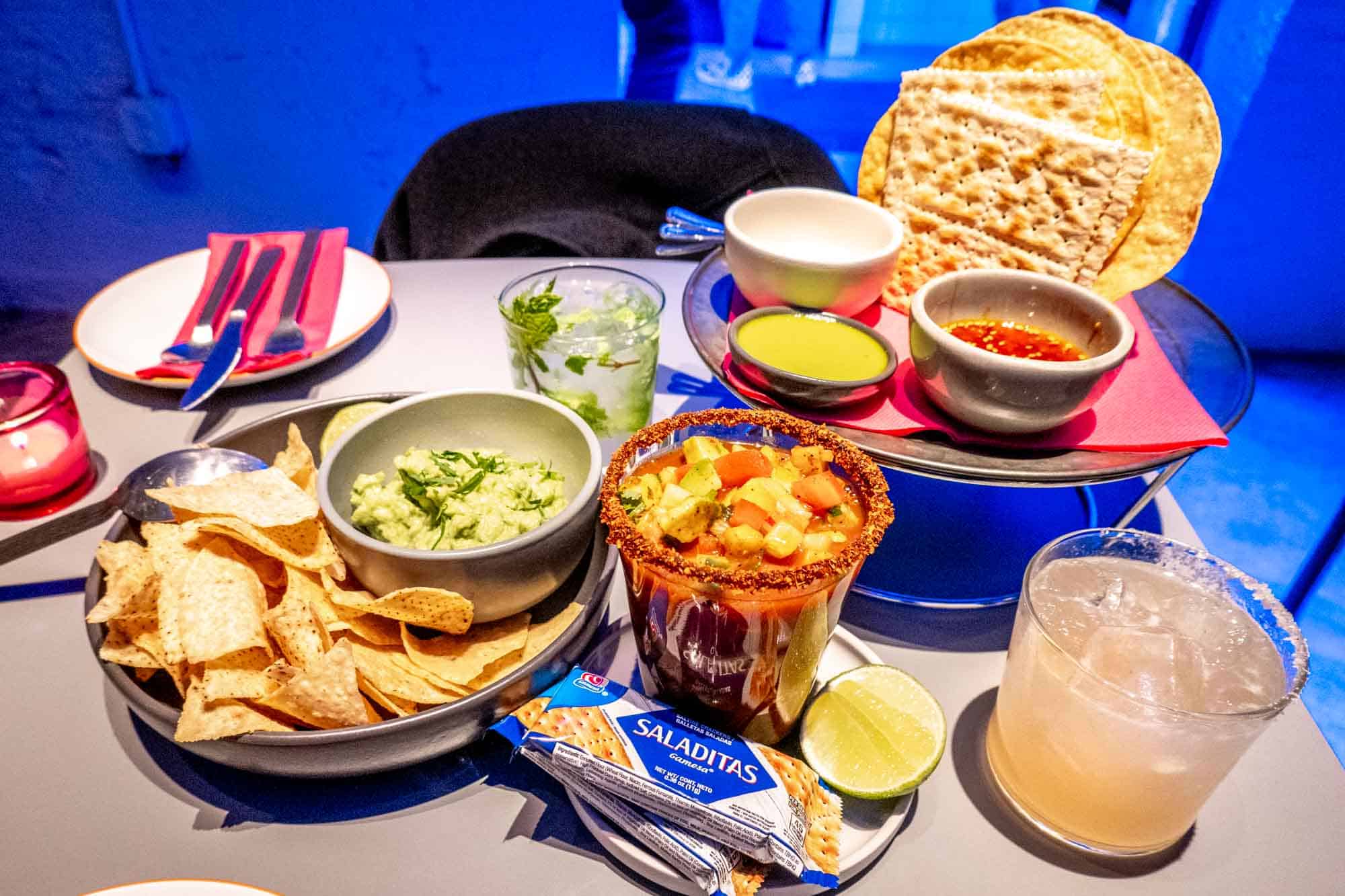 Table with cocktails, tortilla chips and guacamole, ceviche, and other Mexican food