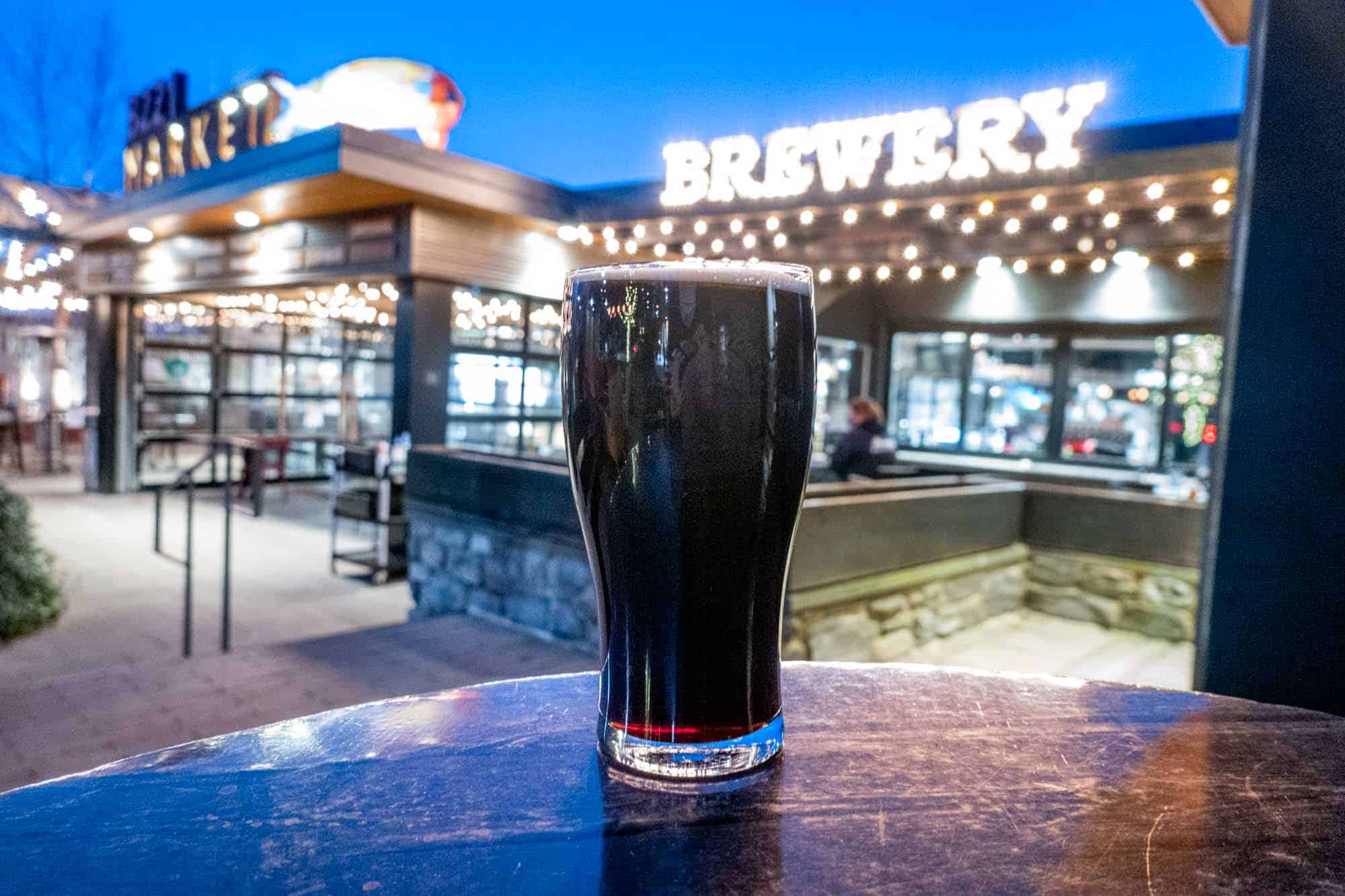 Glass of beer on table in front of illuminated "brewery" sign